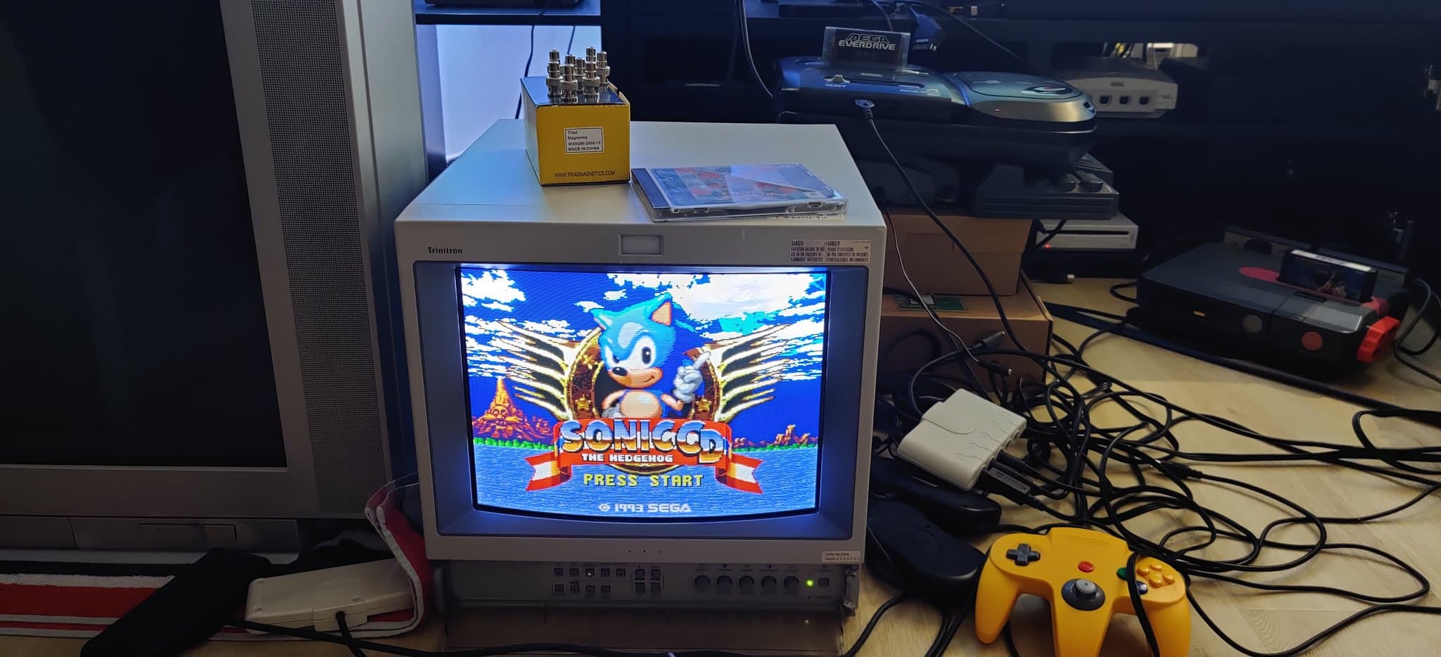 Sega Mega-CD 2 displaying the Sonic CD title screen on a CRT after the fuse replacement, with a yellow N64 controller nearby.
