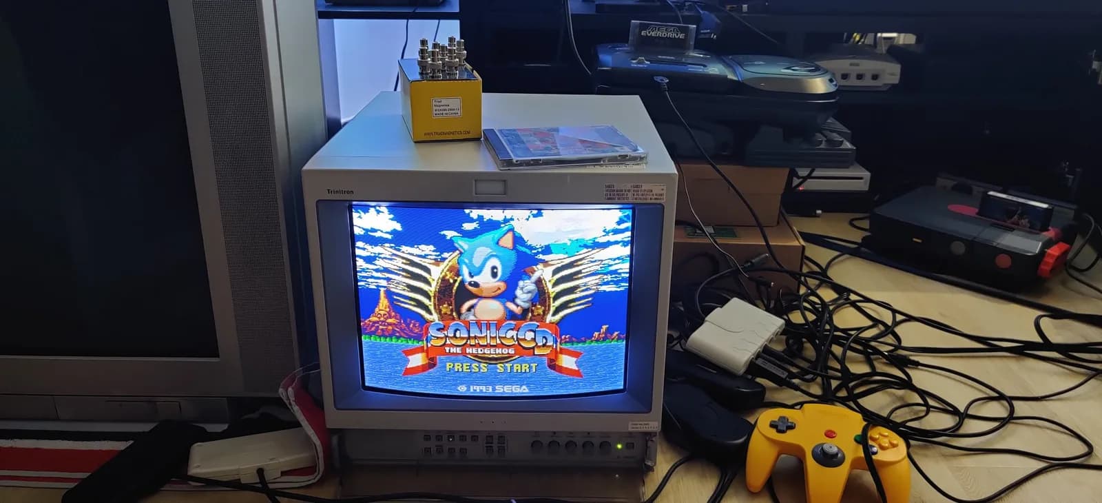 Sega Mega-CD 2 displaying the Sonic CD title screen on a CRT after the fuse replacement, with a yellow N64 controller nearby.