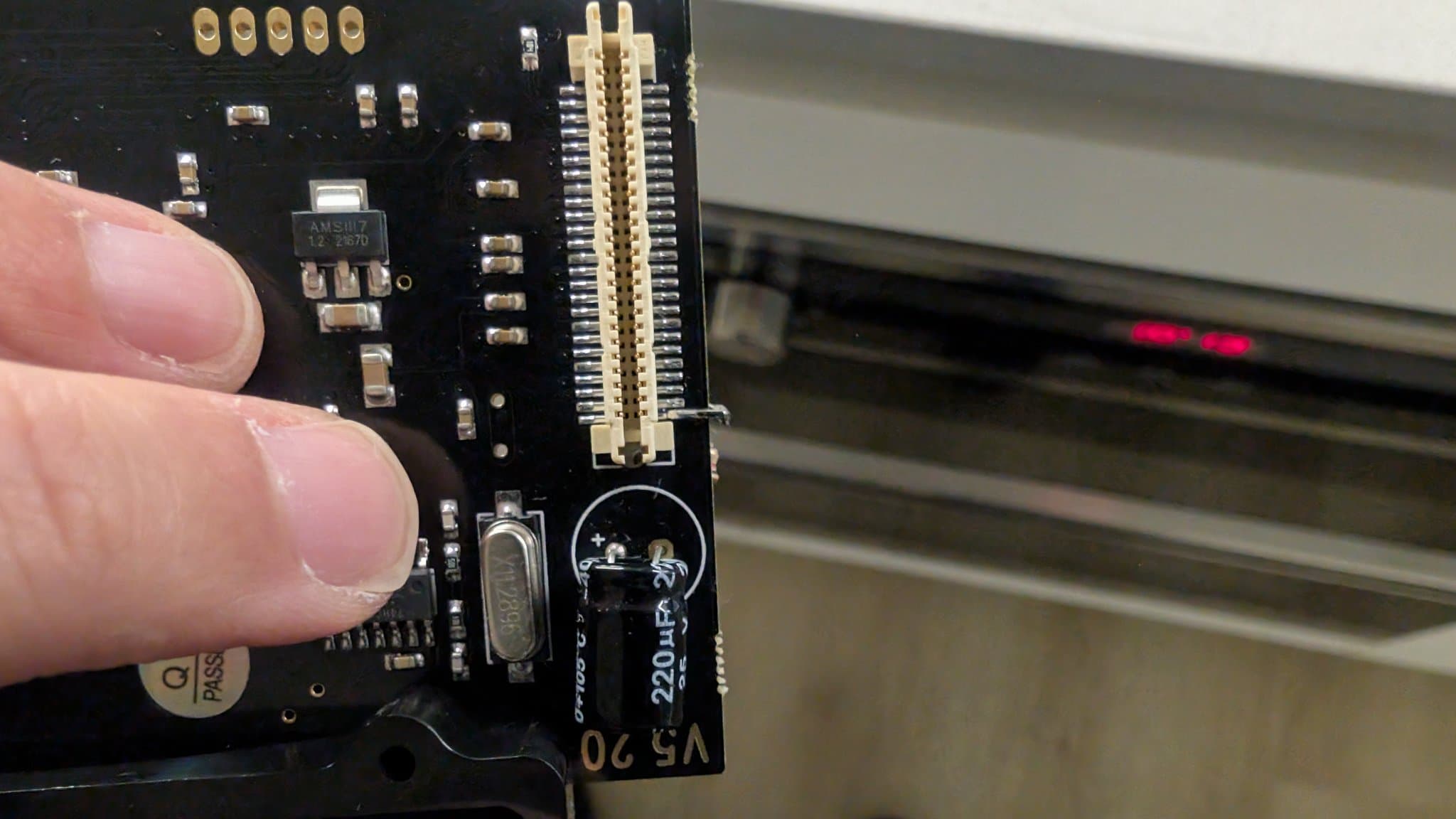 Close-up of the GDEMU board showing its gold edge connector, AMS1117 3.3V regulator, crystal and onboard capacitor.