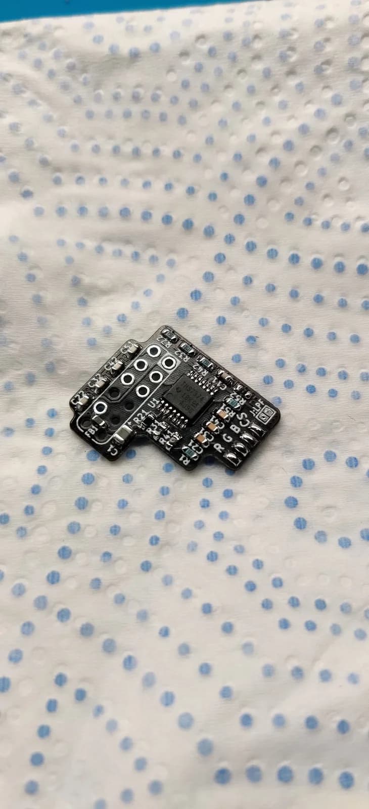 The N64 RGB amp PCB after cleaning with isopropyl alcohol, the video IC now installed and all SMD components soldered in place, on a blue-dotted paper towel.