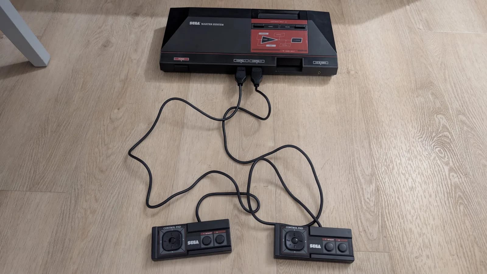 Refurbished Sega Master System MK-2000 with two cleaned Control Pads connected via cables, ready for testing.