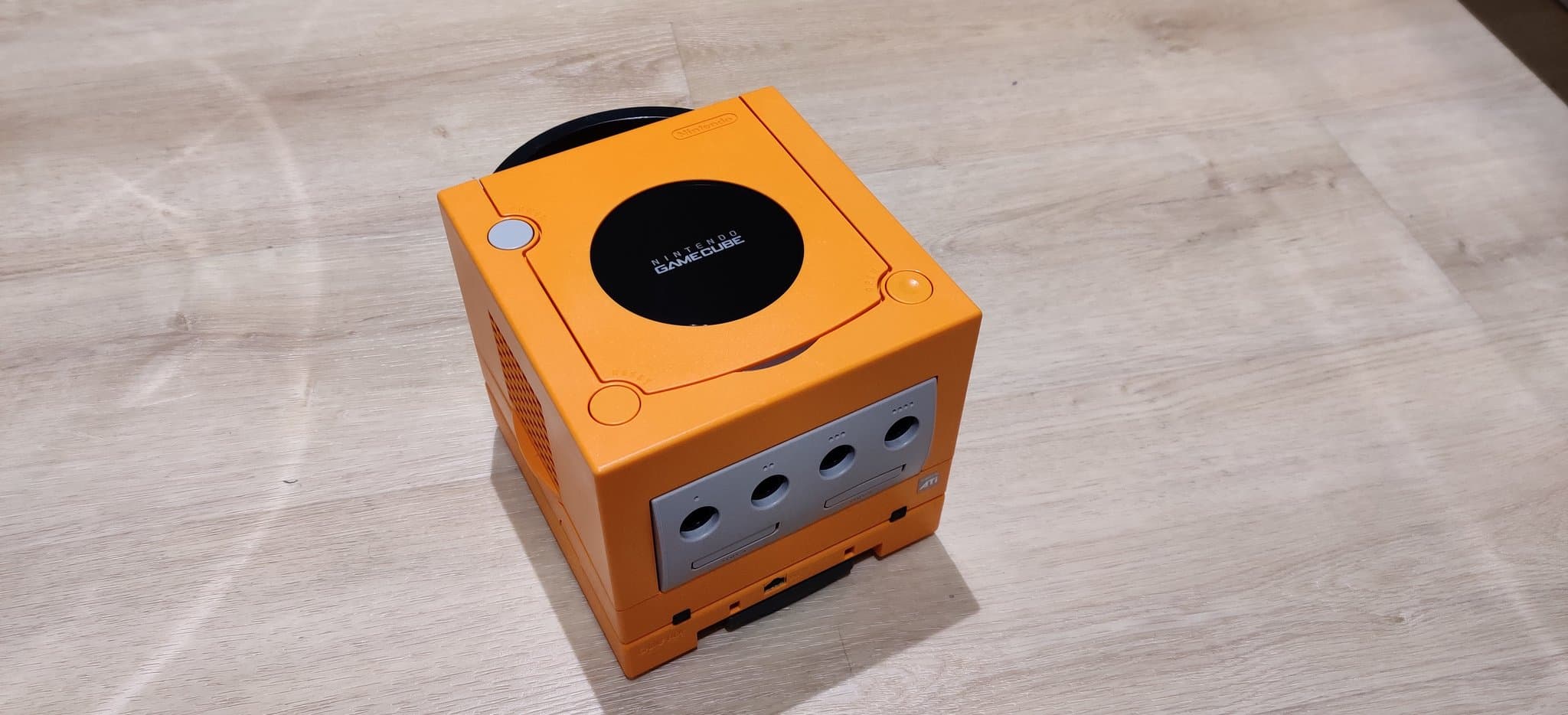Orange spice Nintendo GameCube with controller port access panel open, showing four ports and Xeno chip installation area visible.
