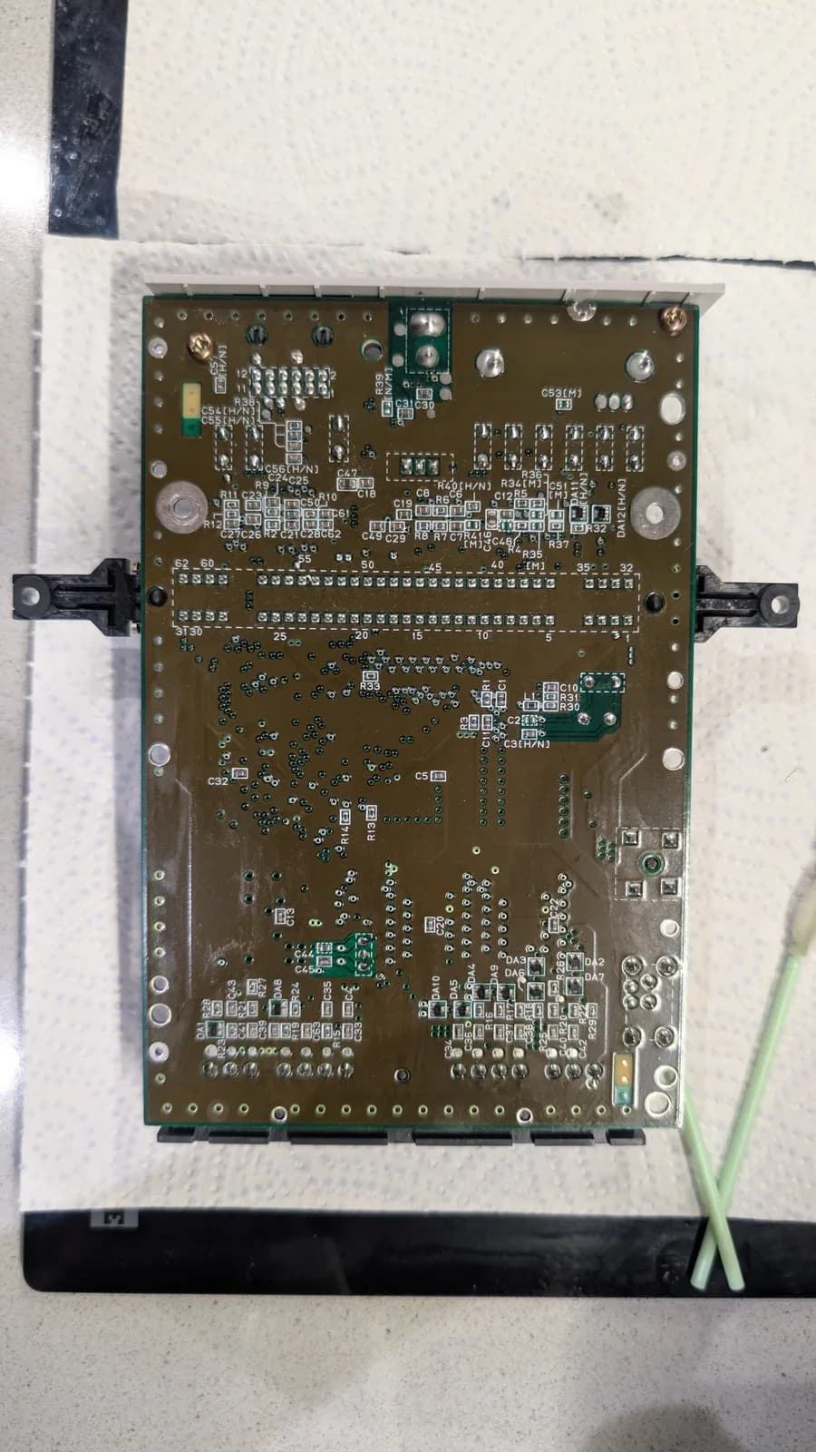 Recapped Super Famicom Jr. motherboard with new voltage regulator, clean solder joints, and organized component layout on work surface.
