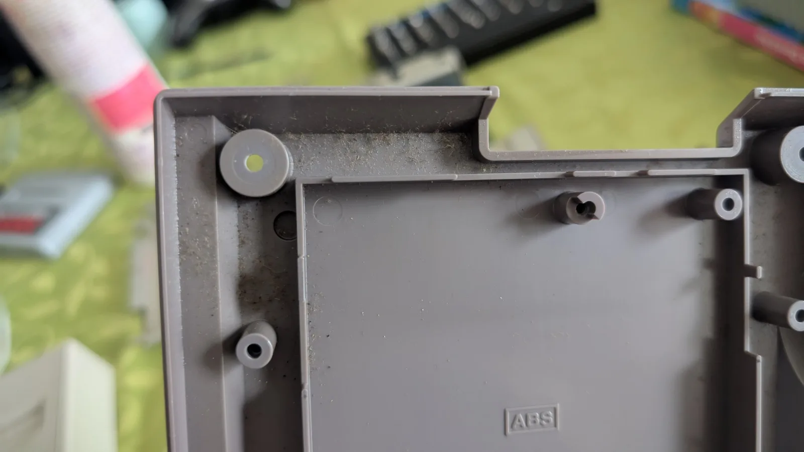 Inside a corner of the AV Famicom's gray plastic shell (stamped ABS), showing screw-boss mounting posts and built-up dust and grime along the inner walls.