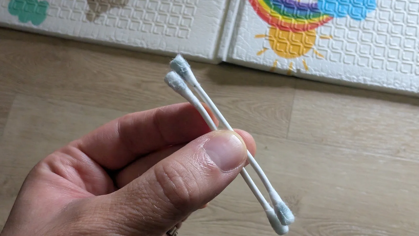 Two cotton swabs held in hand, their tips soiled greyish from cleaning the oxidation out of the AV Famicom's cartridge slot.