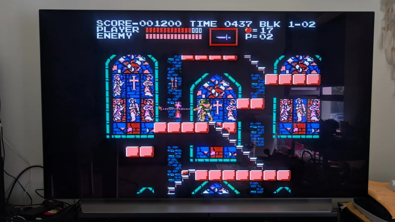 Castlevania III (Akumajo Densetsu) gameplay on an LG C1 OLED TV, output from the AV Famicom after the cartridge-slot clean. HUD reads SCORE 001200, BLK 1-02, with the whip-wielding hero in the first level.