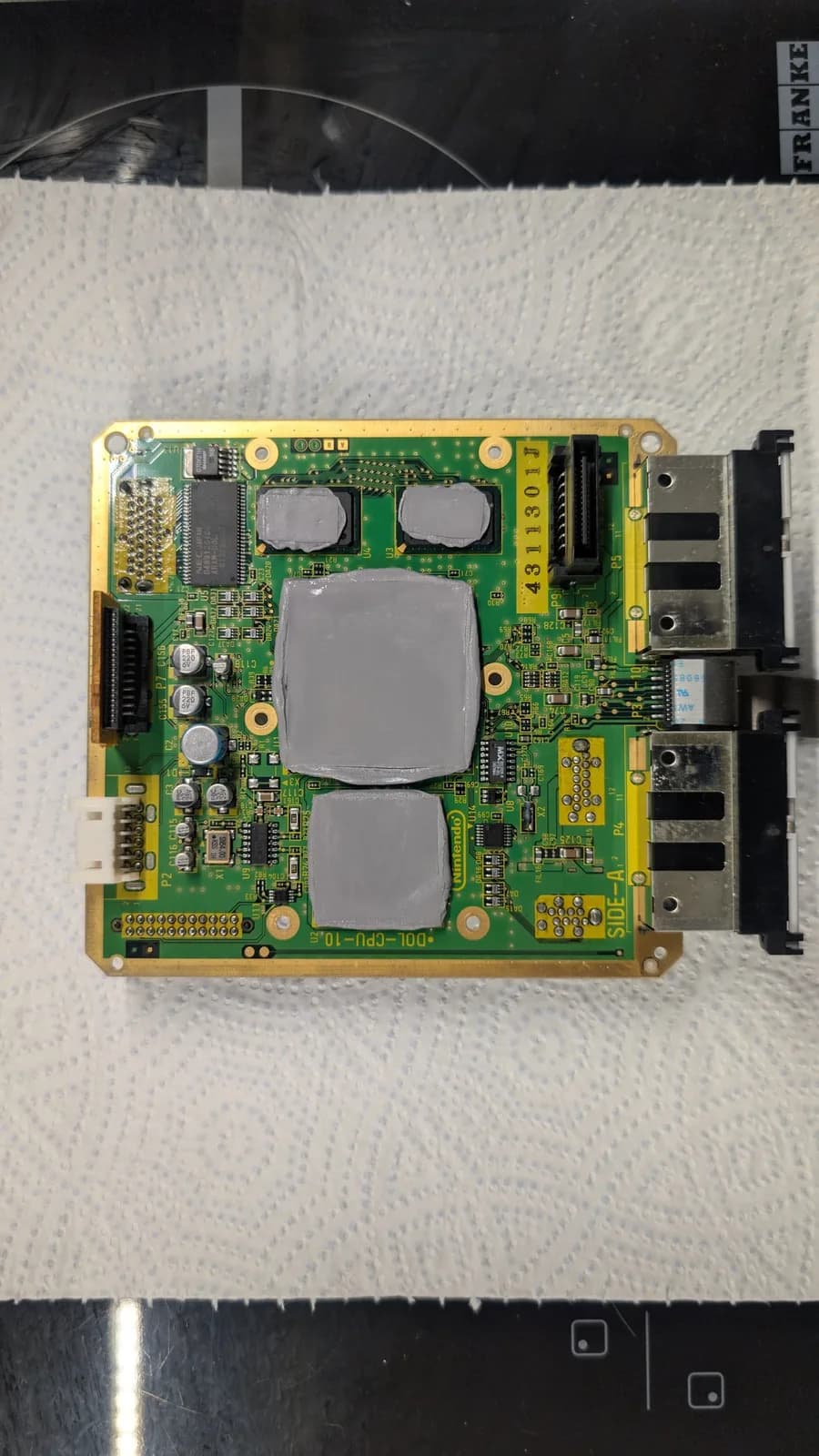 Panasonic Q motherboard with recapped capacitors, two large heatsinks, and black connectors visible during FlippyDrive reinstallation.