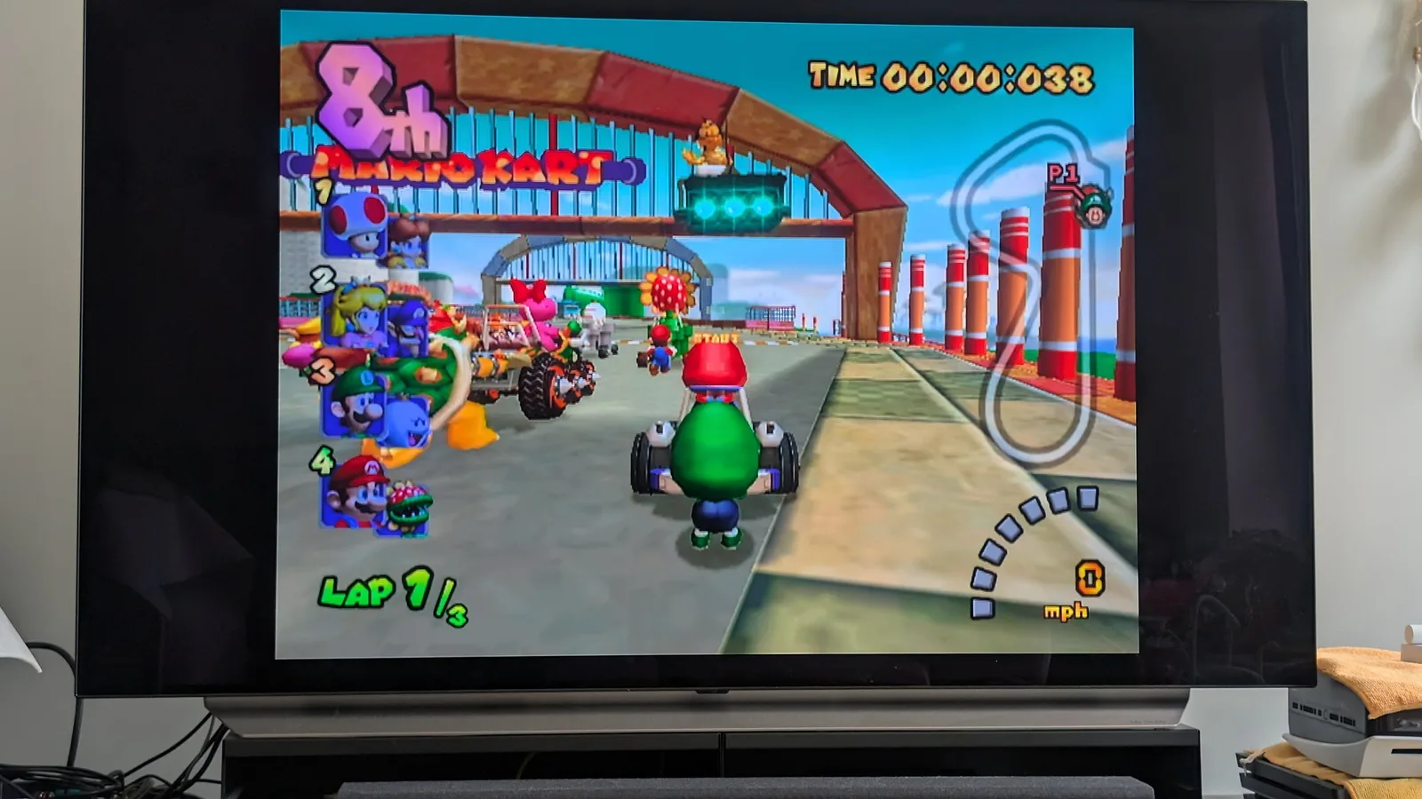 Mario Kart: Double Dash gameplay on restored Panasonic Q, showing start line at Luigi Circuit with green Yoshi kart ready to race.