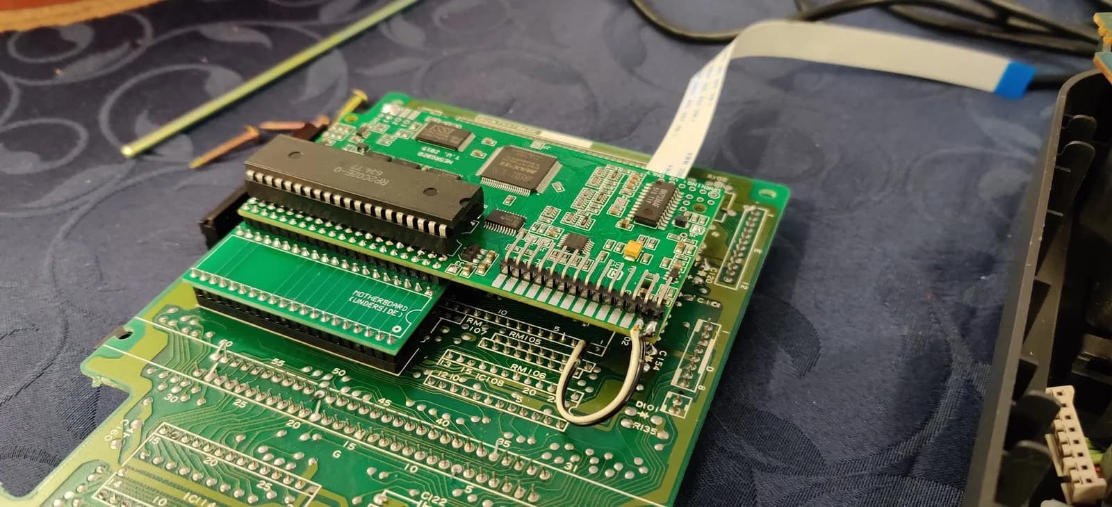Green NESRGB daughterboard installed on the Sharp Twin Famicom motherboard, the original CPU/PPU DIP chip re-socketed on top, with a white ribbon cable attached to the NESRGB board but not yet connected to anything else.
