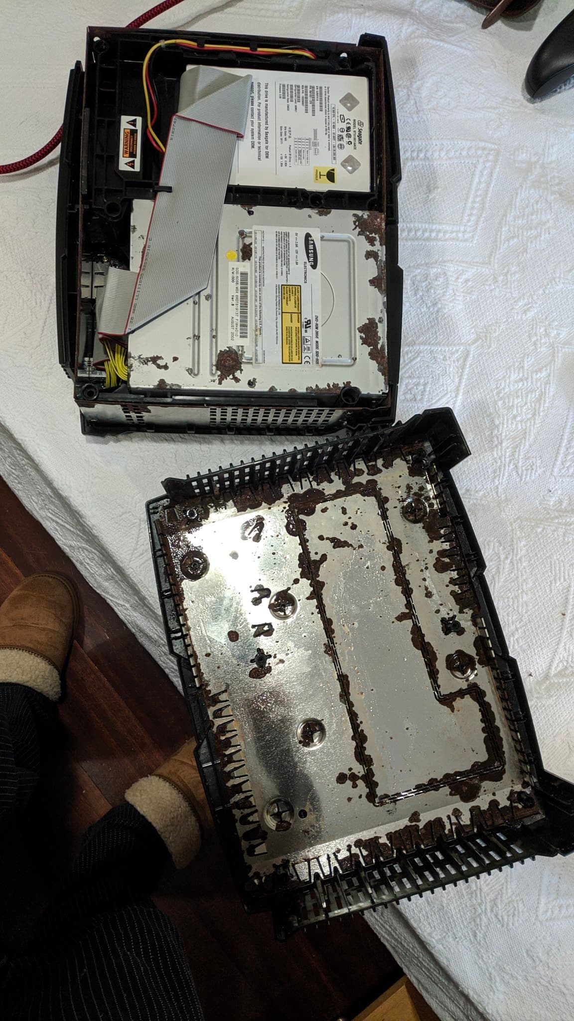 Disassembled OG Xbox showing heavily corroded metal chassis and optical drive assembly with visible rust, capacitors, and ribbon cables during refurbishment.