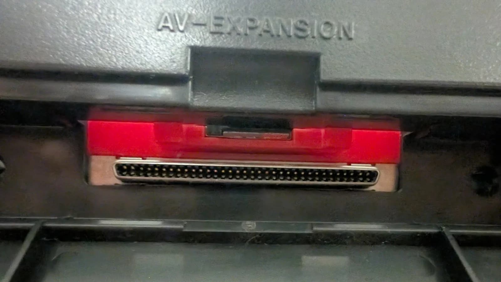 Close-up of the Panasonic FZ-1's "AV-EXPANSION" bay, showing the console's own multi-pin connector in the opening and the red housing that the SD card extender fits into.