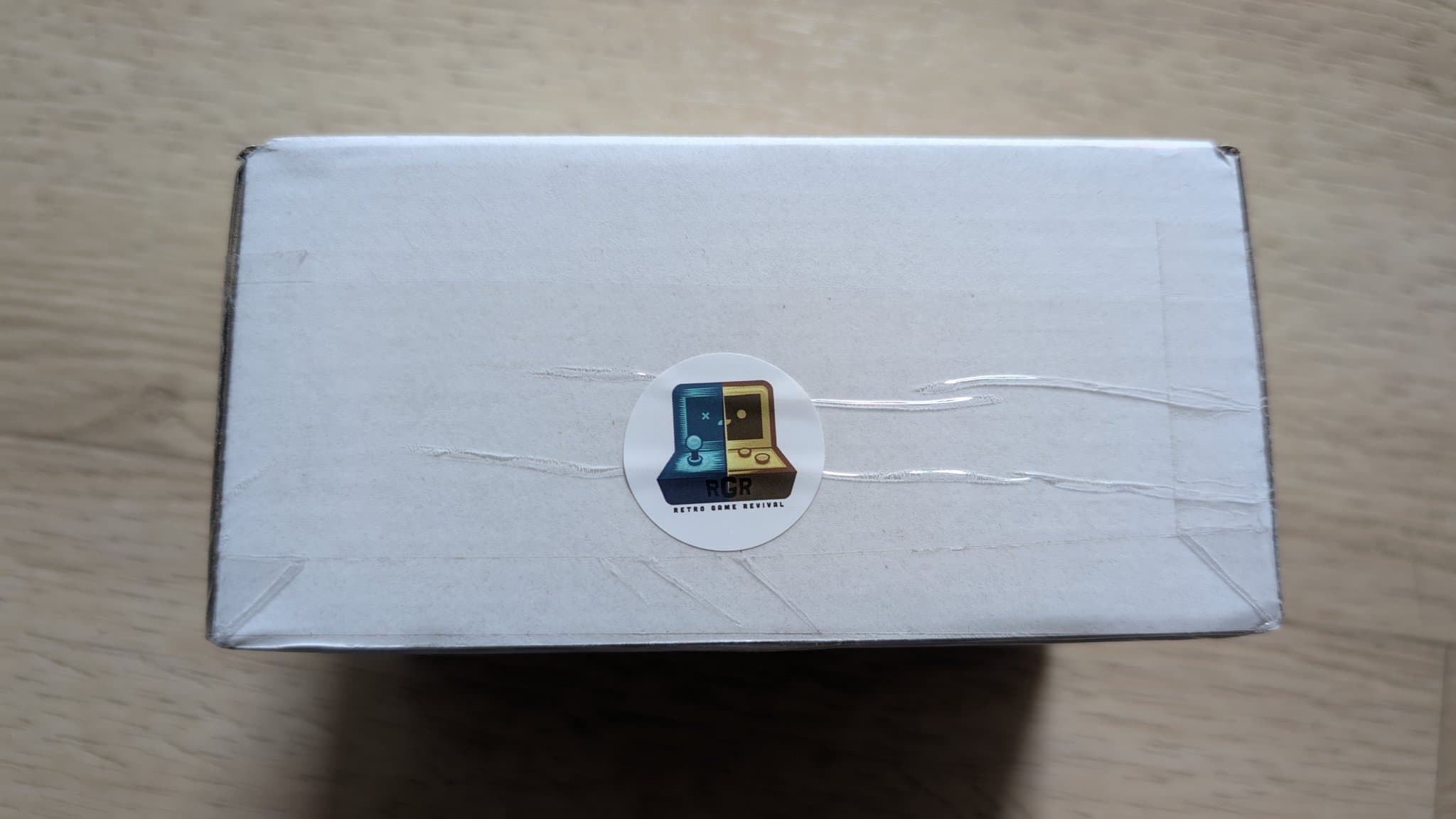 White box with circular Sega Game Gearish logo sticker, containing aftermarket Nomad battery pack from PointerFunction.