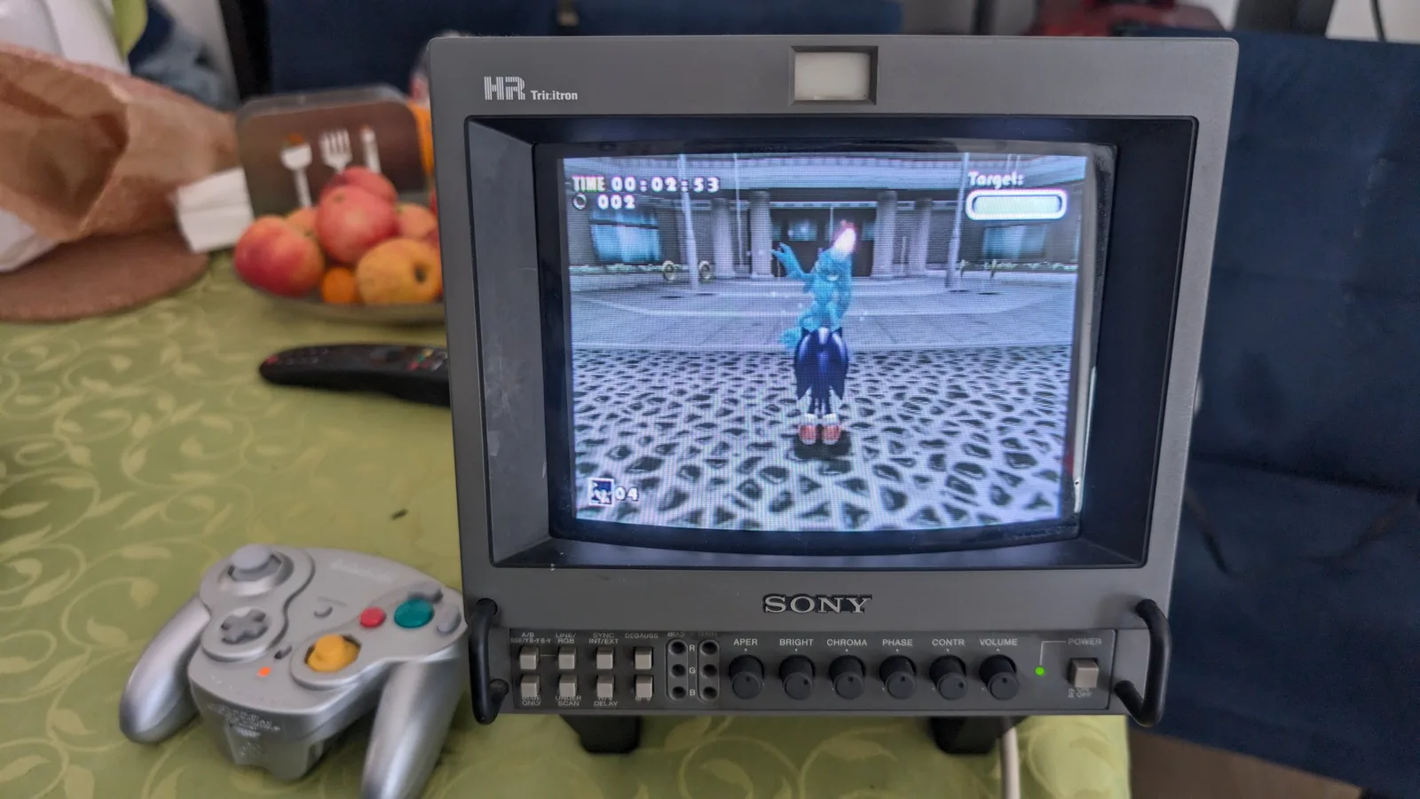 A Sony 9045Q professional CRT displaying Sonic Adventure DX with its on-screen HUD (timer and ring count) visible, a platinum WaveBird wireless GameCube controller beside it, testing the freshly recapped black GameCube.