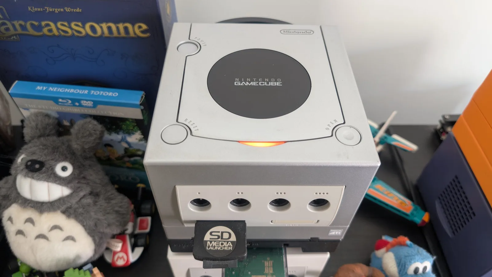 Silver Nintendo GameCube with SD Media Launcher installed, four controller ports visible, power LED lit during mainboard recap restoration project.
