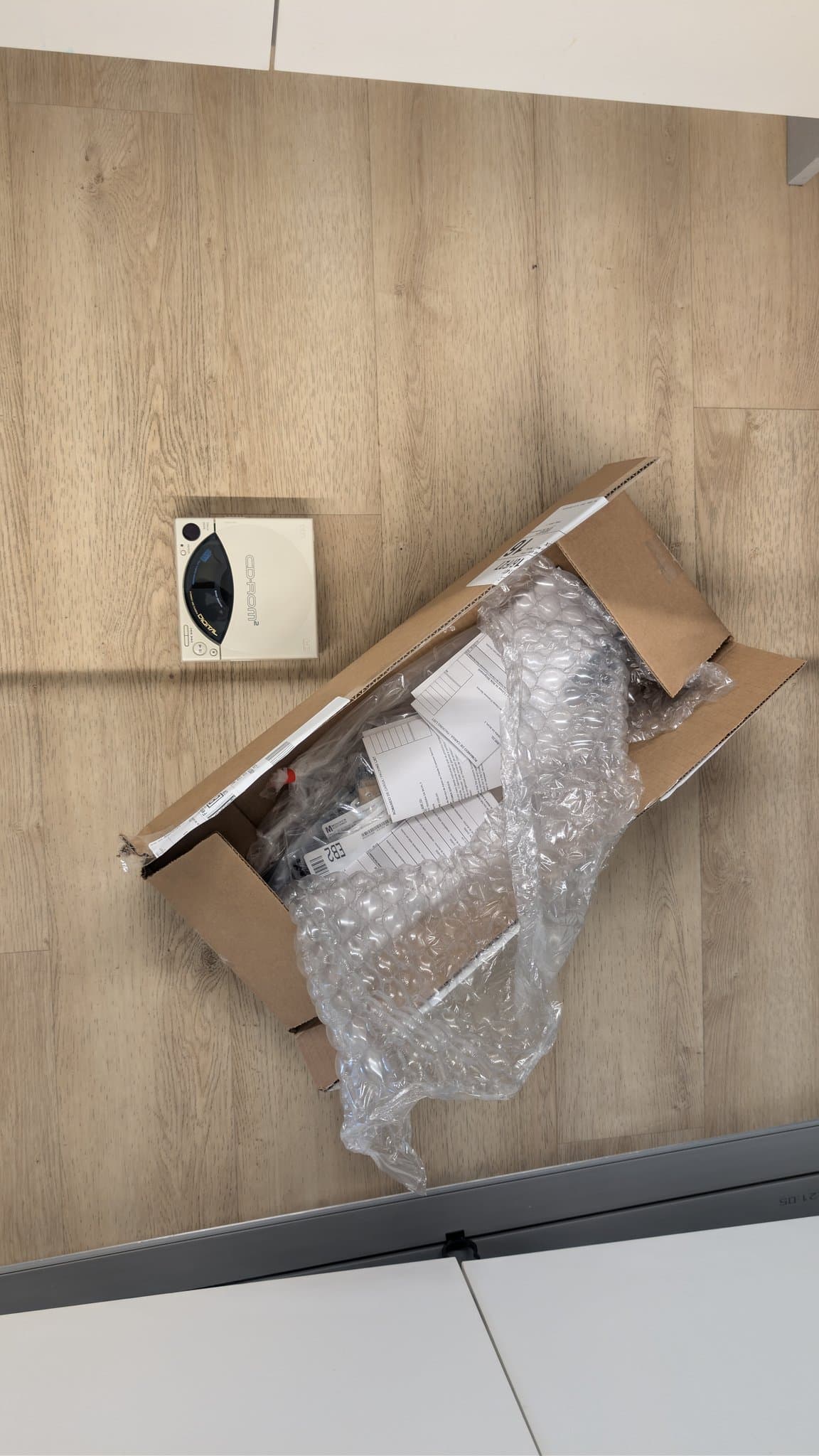 Fully assembled PC Engine CD-ROM2 unit on the floor, next to an opened box of components ordered from Mouser (capacitors and other parts).