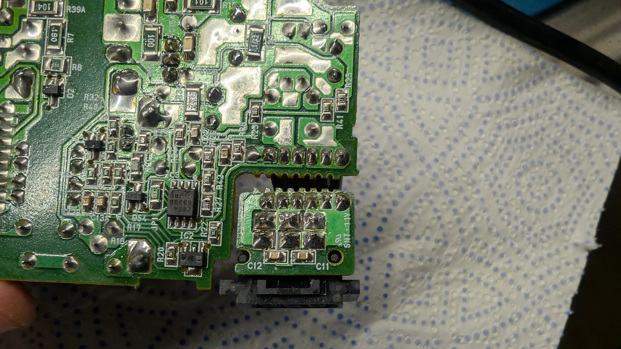 Close-up of the N64 PSU board showing the reflowed solder joints near the power connector after the recap.