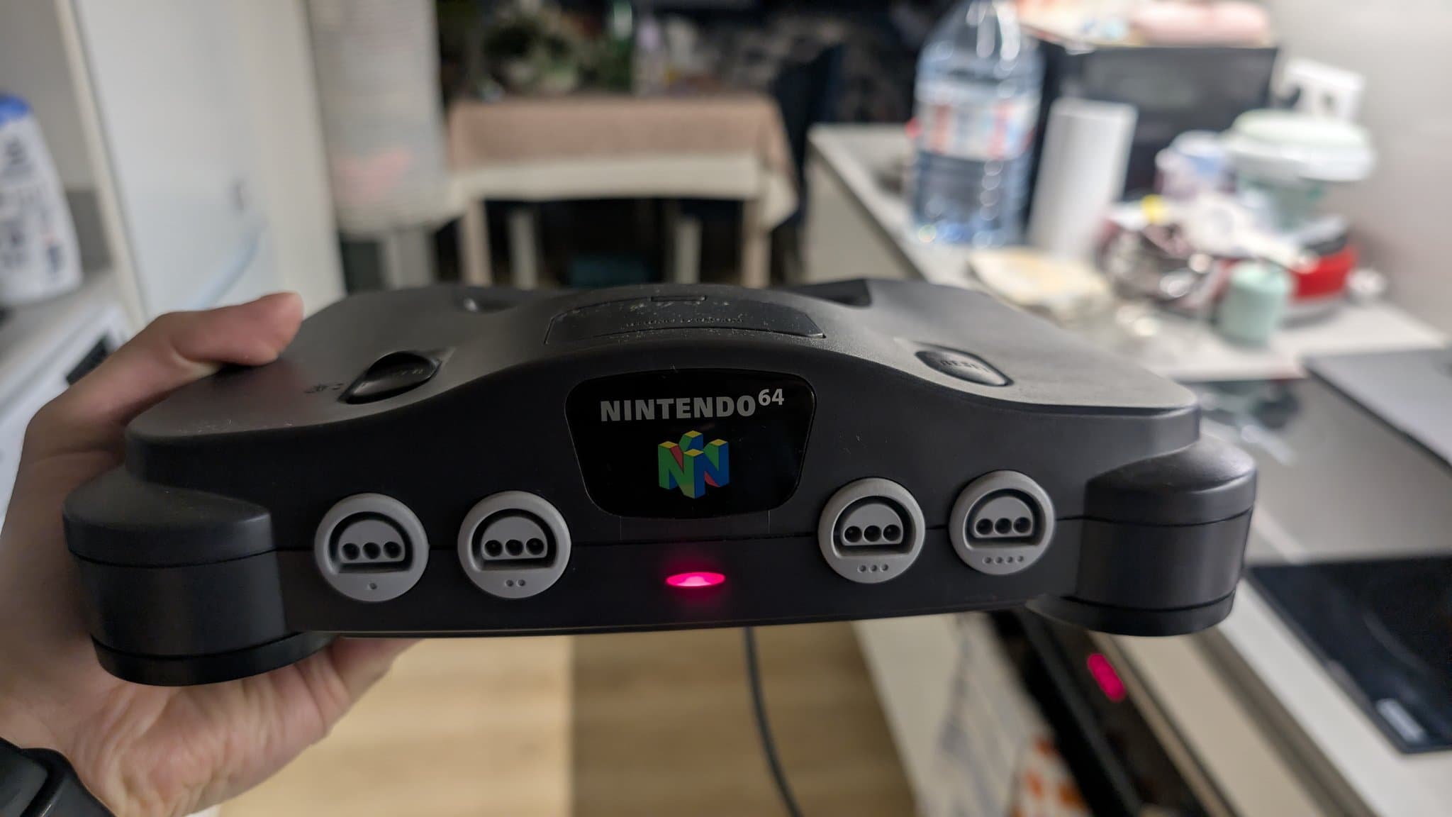 The whole Nintendo 64 console held in hand, powered on and working again after the service, the no-power fault fixed.