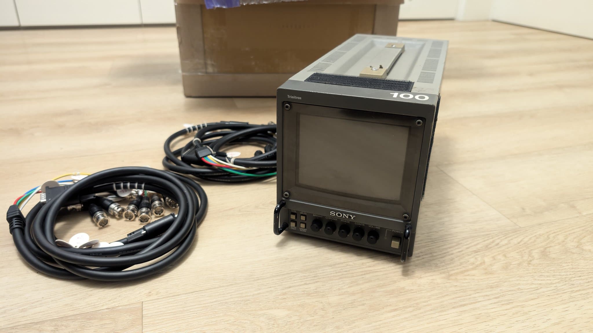 Sony PVM-6041Q 6" CRT monitor with BNC cable connectors and multicolored VGA-to-BNC cables on wooden surface.