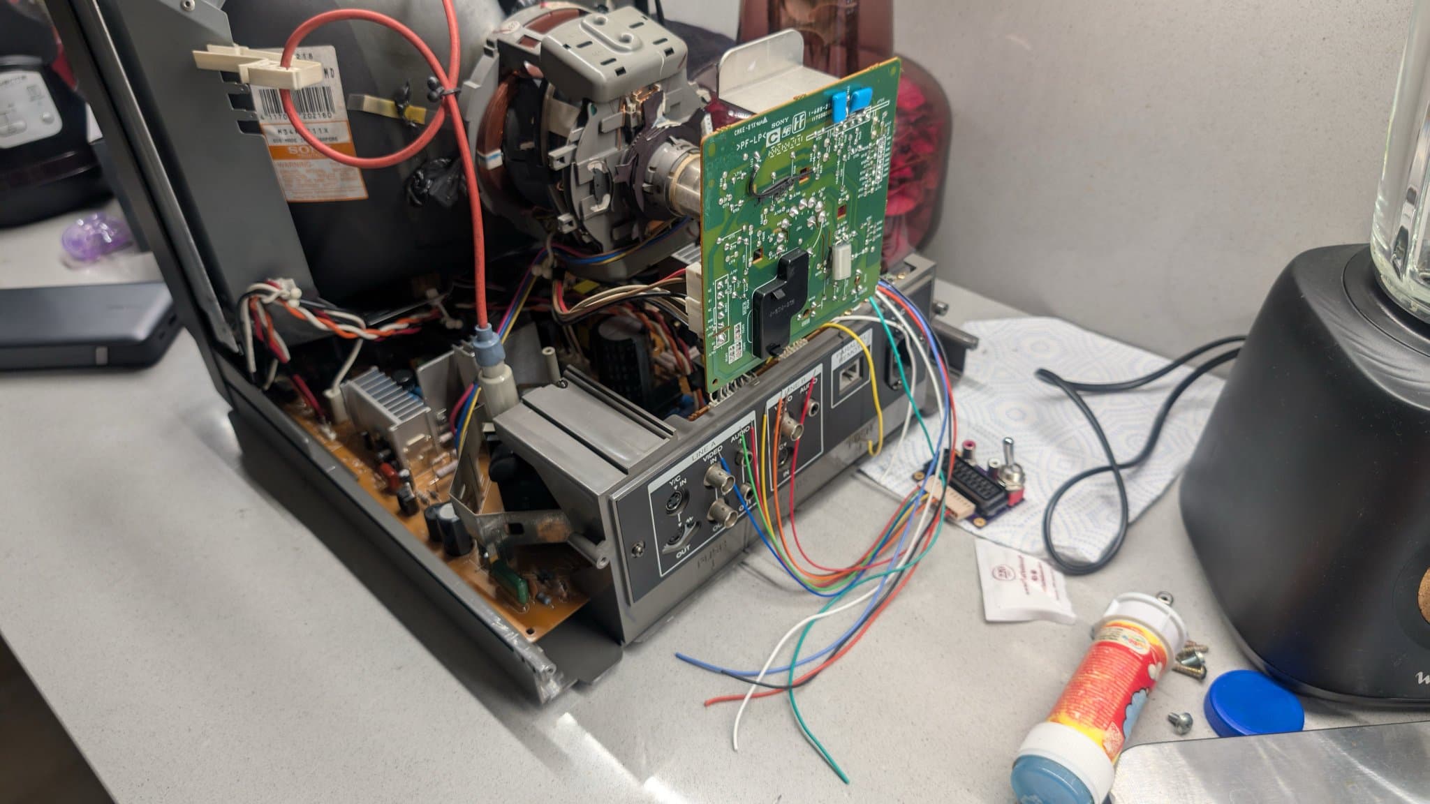 RGB mod PCB with multicolored wires connected to input board connector; heat-shrink tubing visible on solder joints during PVM-14L1 modification.