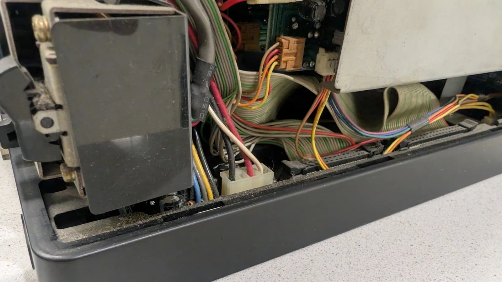An inside view of the Sharp X68000 showing ribbon cables and wires, the power button section, and a partial view of one of the floppy drives.