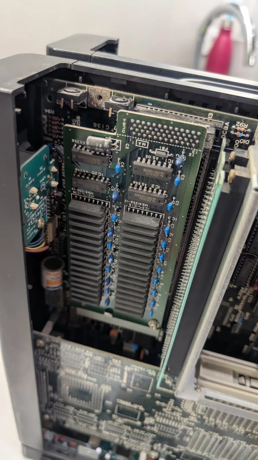 The Sharp X68000's original 1MB RAM expansion board, the Sharp CZ-6BE1, sitting loose in the chassis, its memory chips and blue capacitors visible.