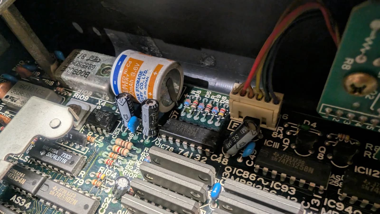 The Sharp X68000 main board before cleaning, showing the battery-leakage corrosion spread across the surrounding area: capacitors, resistors, IC legs and the oscillator.
