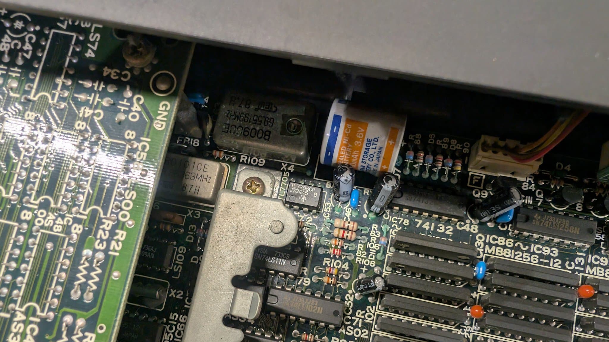 Battery leakage corrosion on X68000 motherboard cleaned with vinegar; visible capacitors, ICs, and corroded traces partially restored.