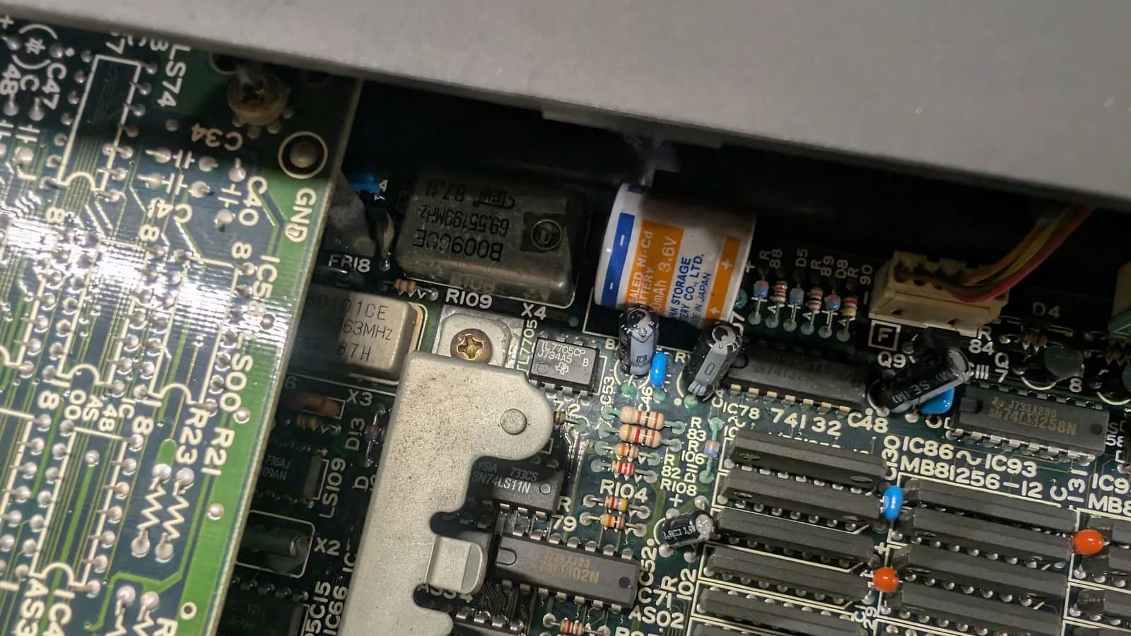 Another angle of the same battery-leakage corrosion on the Sharp X68000 main board before cleaning, some components clearly covered in green corrosion.