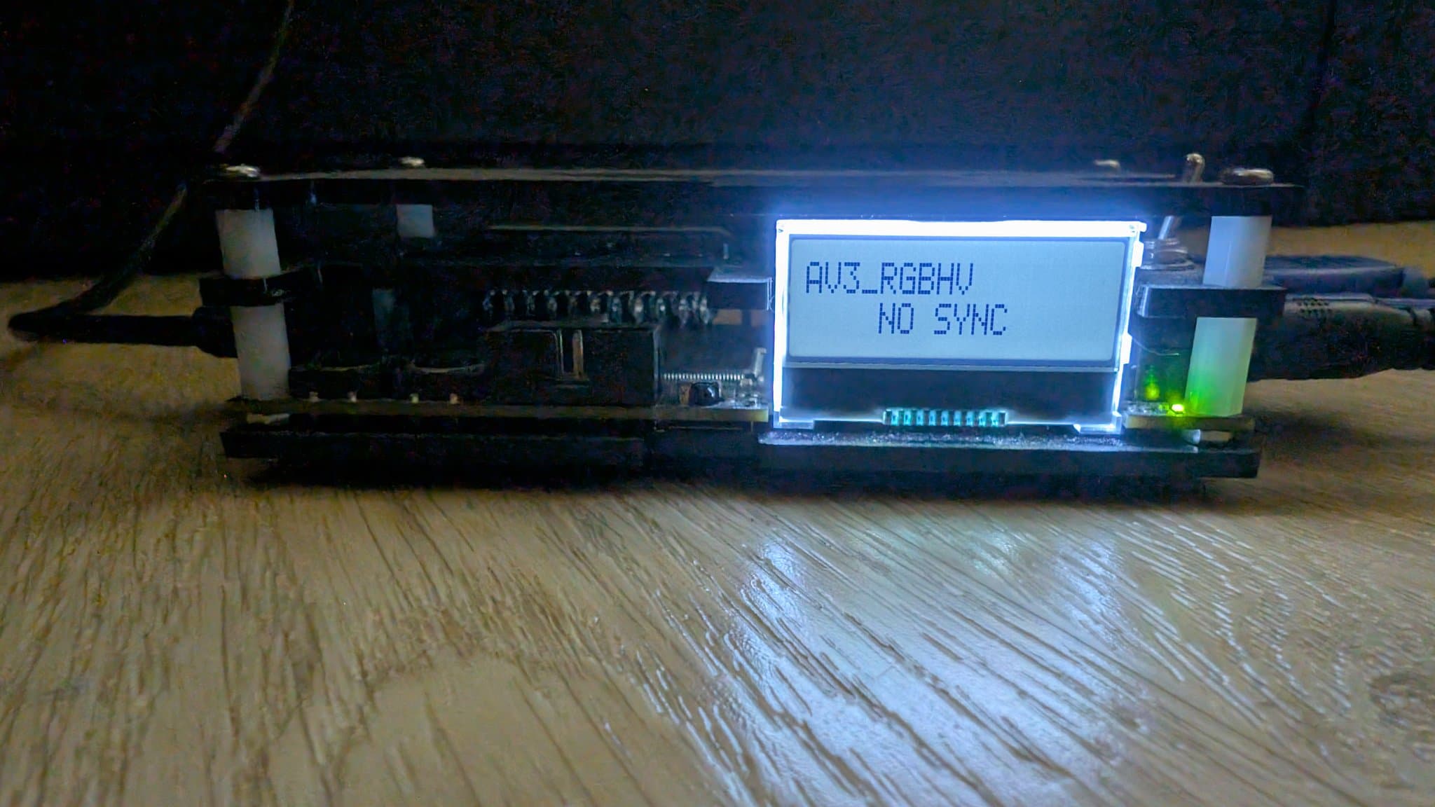 Sharp X68000 with VGA adapter and OSSC displaying "AUZ_RGBHU NO SYNC" on LCD screen; green LED lit, wooden workbench surface.