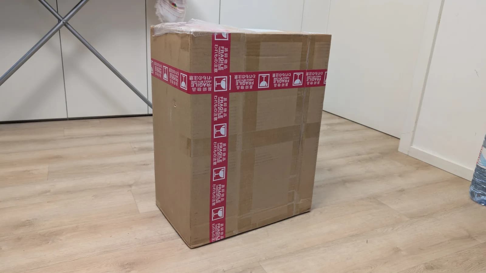 The unopened cardboard shipping box with red fragile tape and Japanese text on the floor, the newly arrived Sharp X68000 inside.