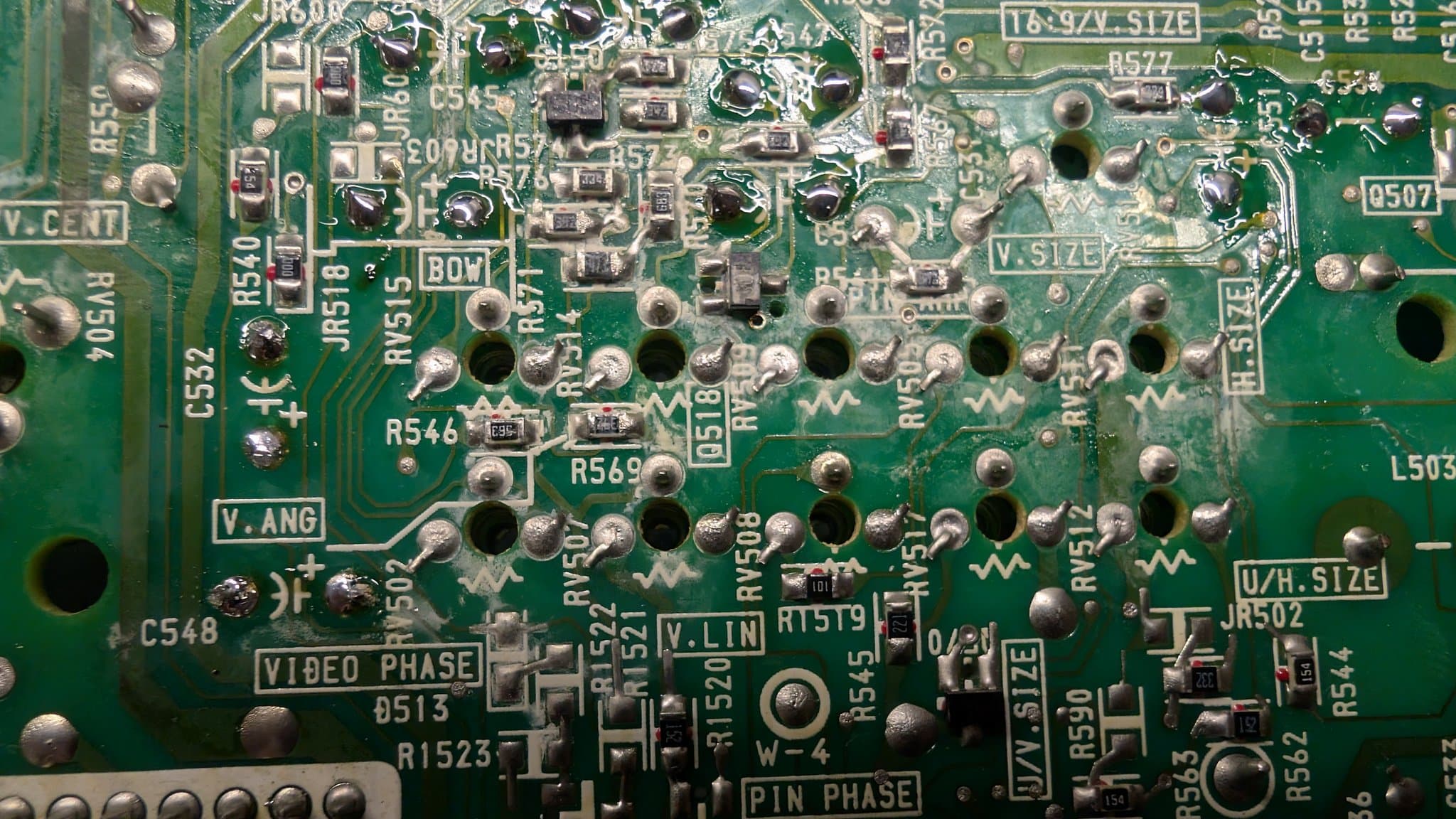 Close-up of Sony PVM-9041Q deflection board showing corroded solder joints, component labels (R546, R569, C548, VIDEO PHASE, PIN PHASE), and oxidized solder requiring reflowing during restoration.