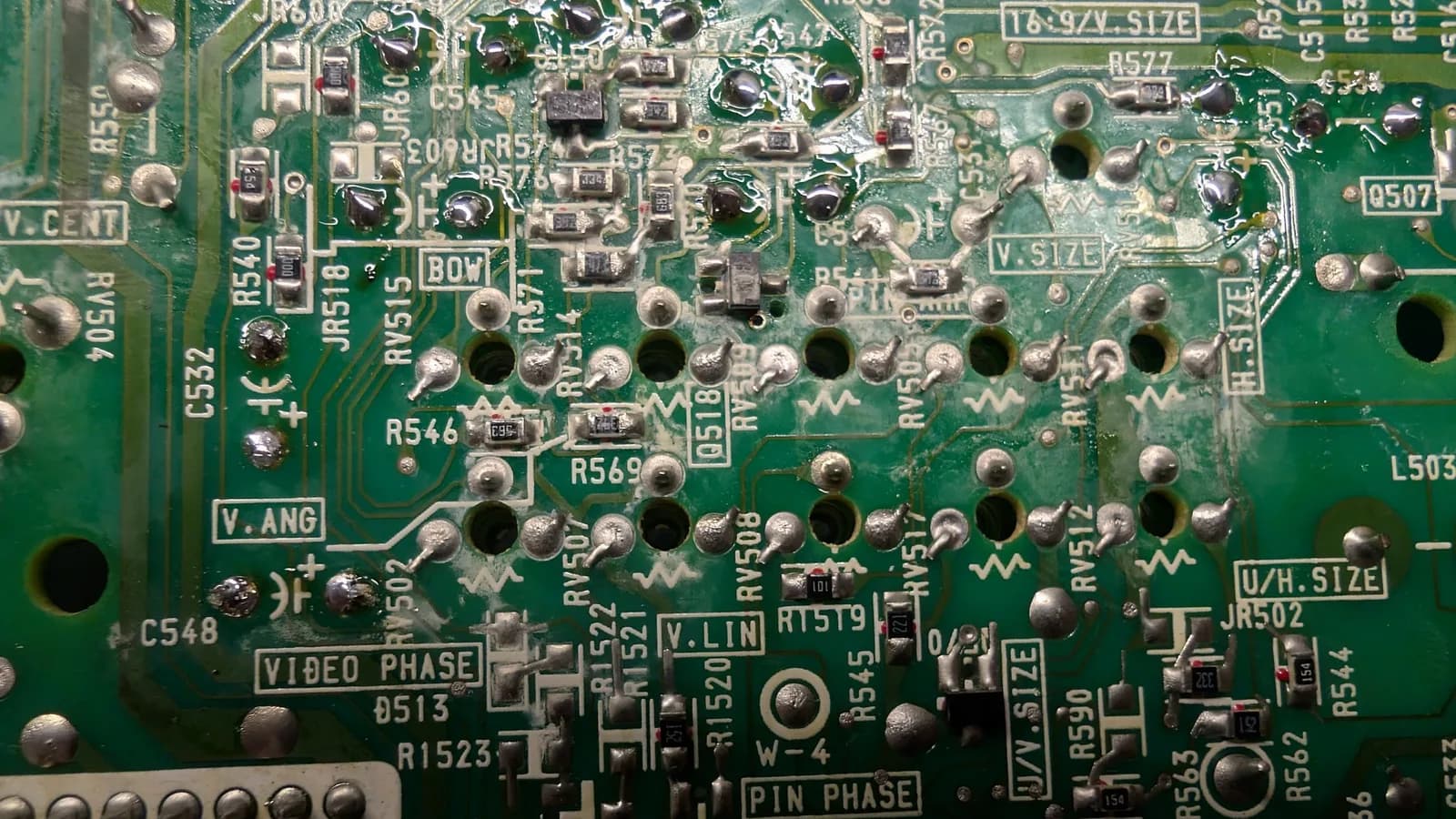 Close-up of the Sony PVM-9045QD deflection board solder side mid-reflow, some joints freshly reflowed and shiny while others are still the grainy old factory solder needing touch-up.