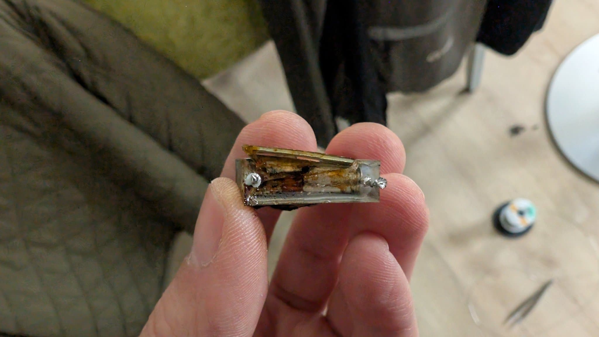 Burnt-out X2 safety capacitor held in fingers, showing catastrophic thermal damage and internal failure from the Beovision 1 repair.