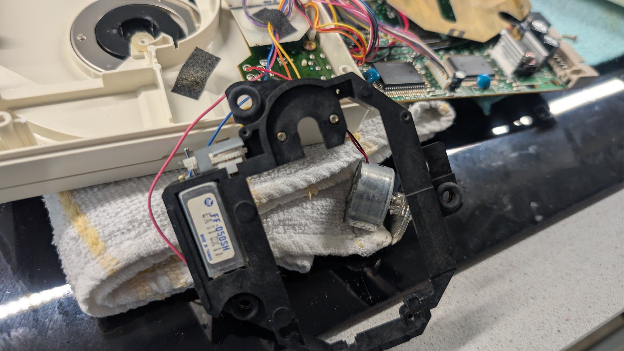 PC Engine CD-ROM2 spindle motor assembly with its mounting bracket and wiring, the wires held by factory tape (not insulation), during the laser transplant.