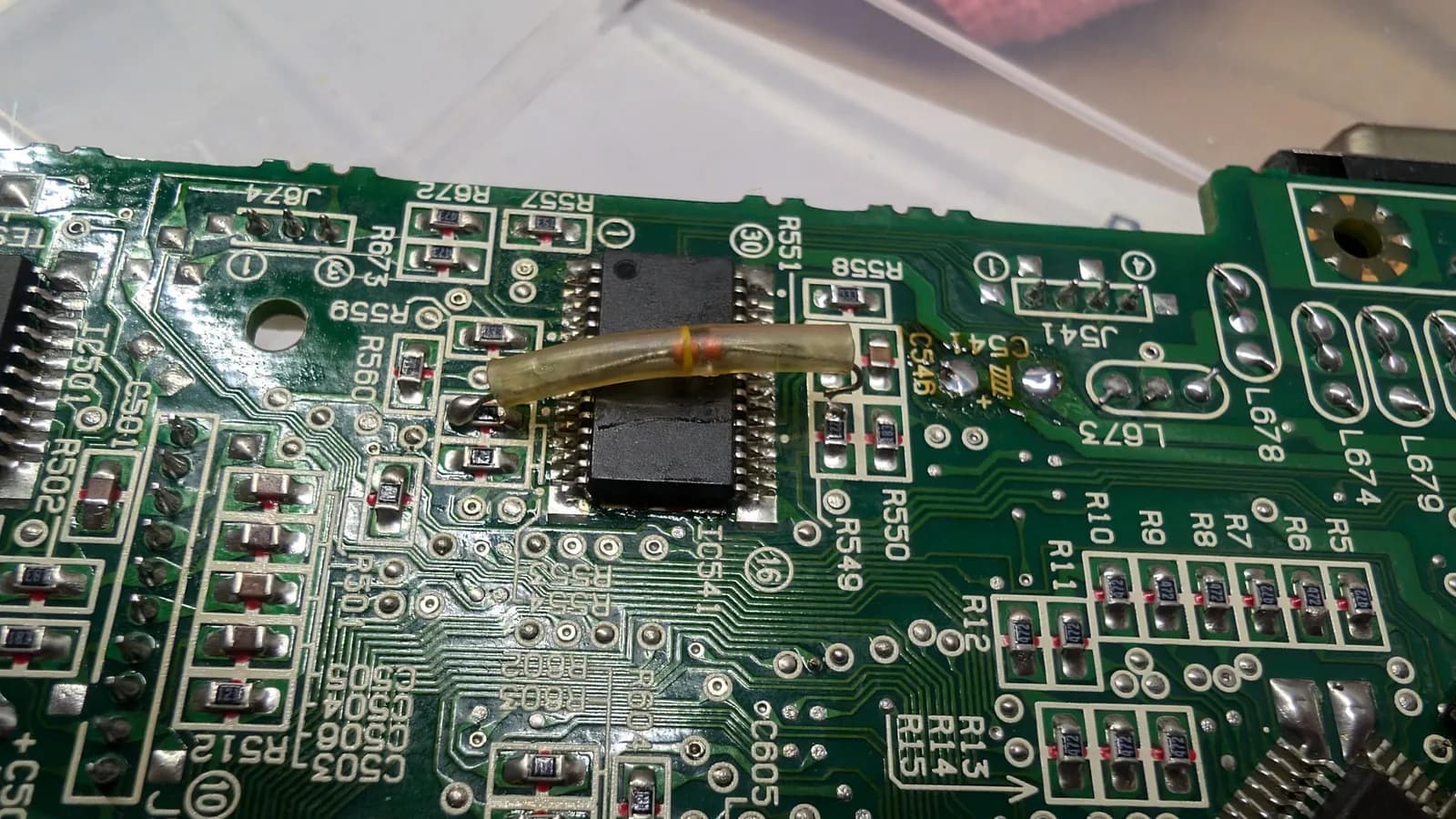 Soldering iron replacing BTL driver IC on corroded Sega Wondermega circuit board with visible component damage and corrosion.