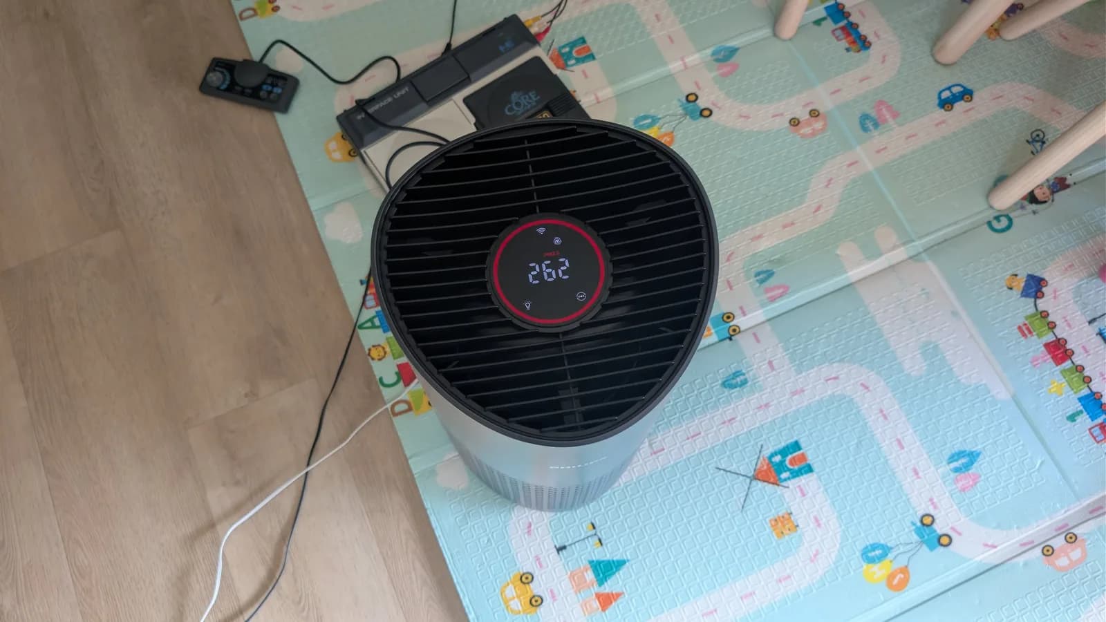 Air purifier displaying 26.2°C on display mat with children's toys, addressing lingering smoke smell from B&O repair.