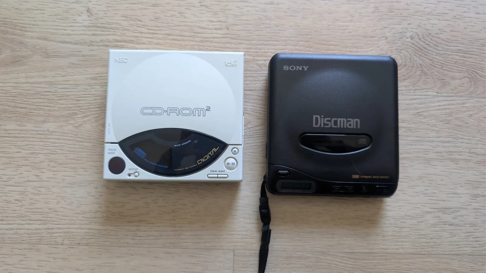 NEC PC Engine CD-ROM2 next to Sony Discman on wooden surface; donor unit for laser replacement during restoration.