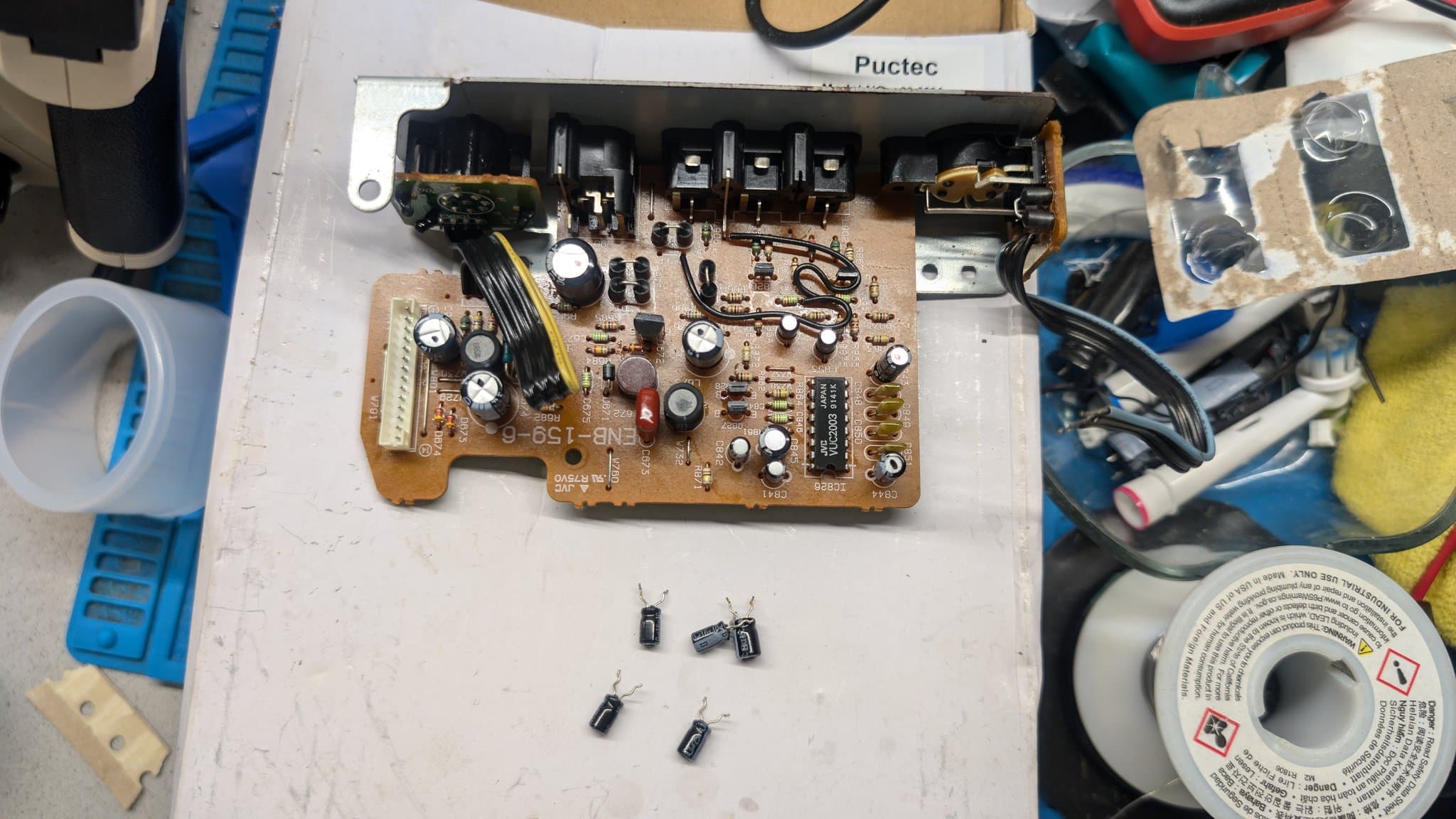 Sega Wondermega AV board with removed electrolytic capacitors displayed below, showing corroded PCB and components requiring replacement during restoration.