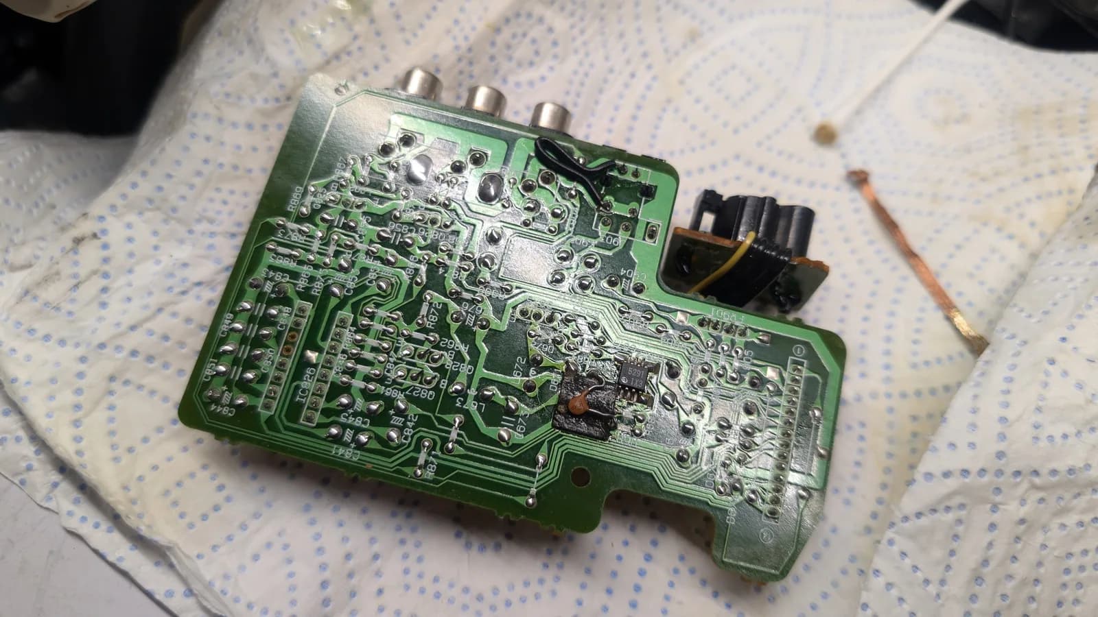 Wondermega AV board with partially recapped electrolytic capacitors and reflowed solder joints, green PCB with three RCA connectors visible.