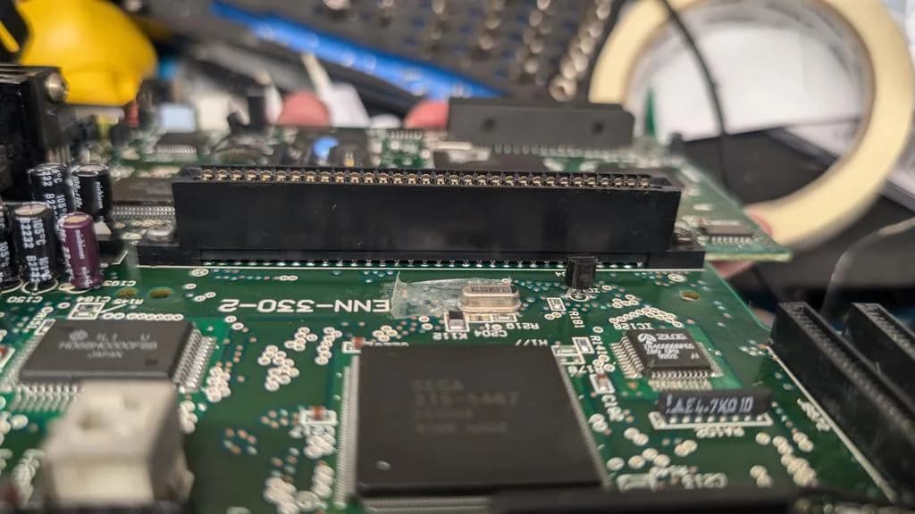 Close-up of Wondermega motherboard showing re-soldered connector and patched trace repair with kynar wire on green PCB.