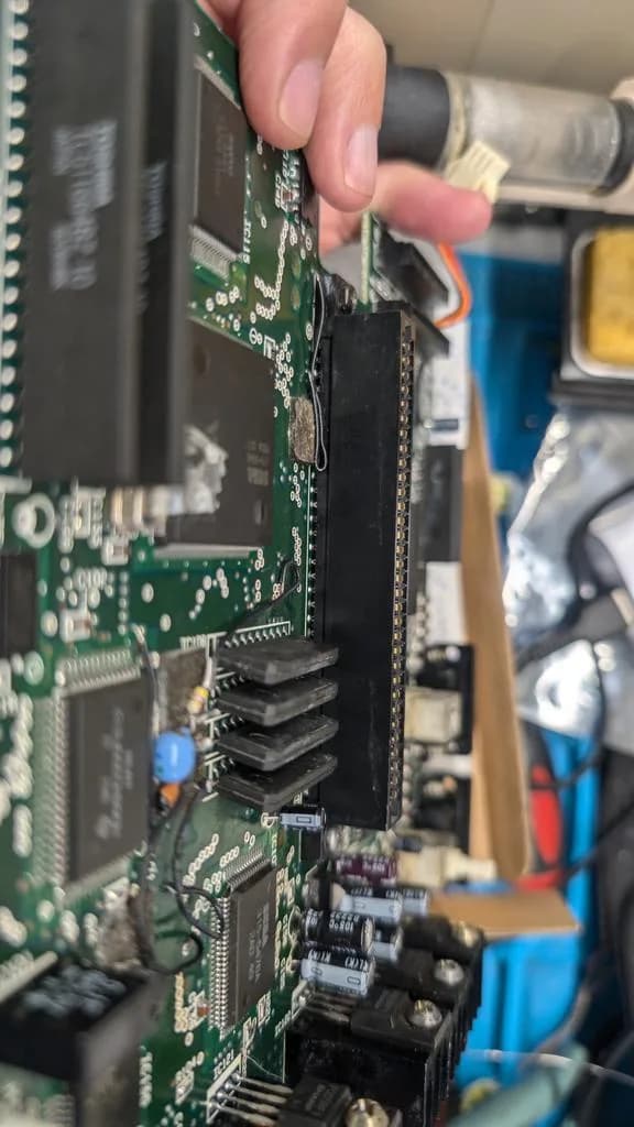 Close-up of repaired connector on Sega Wondermega PCB with fresh solder joints and kynar wire patch on broken trace.