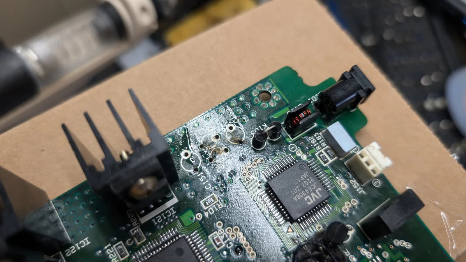 Wondermega mainboard with removed voltage regulator and capacitor, showing exposed solder pads and adjacent IC chips during disassembly.