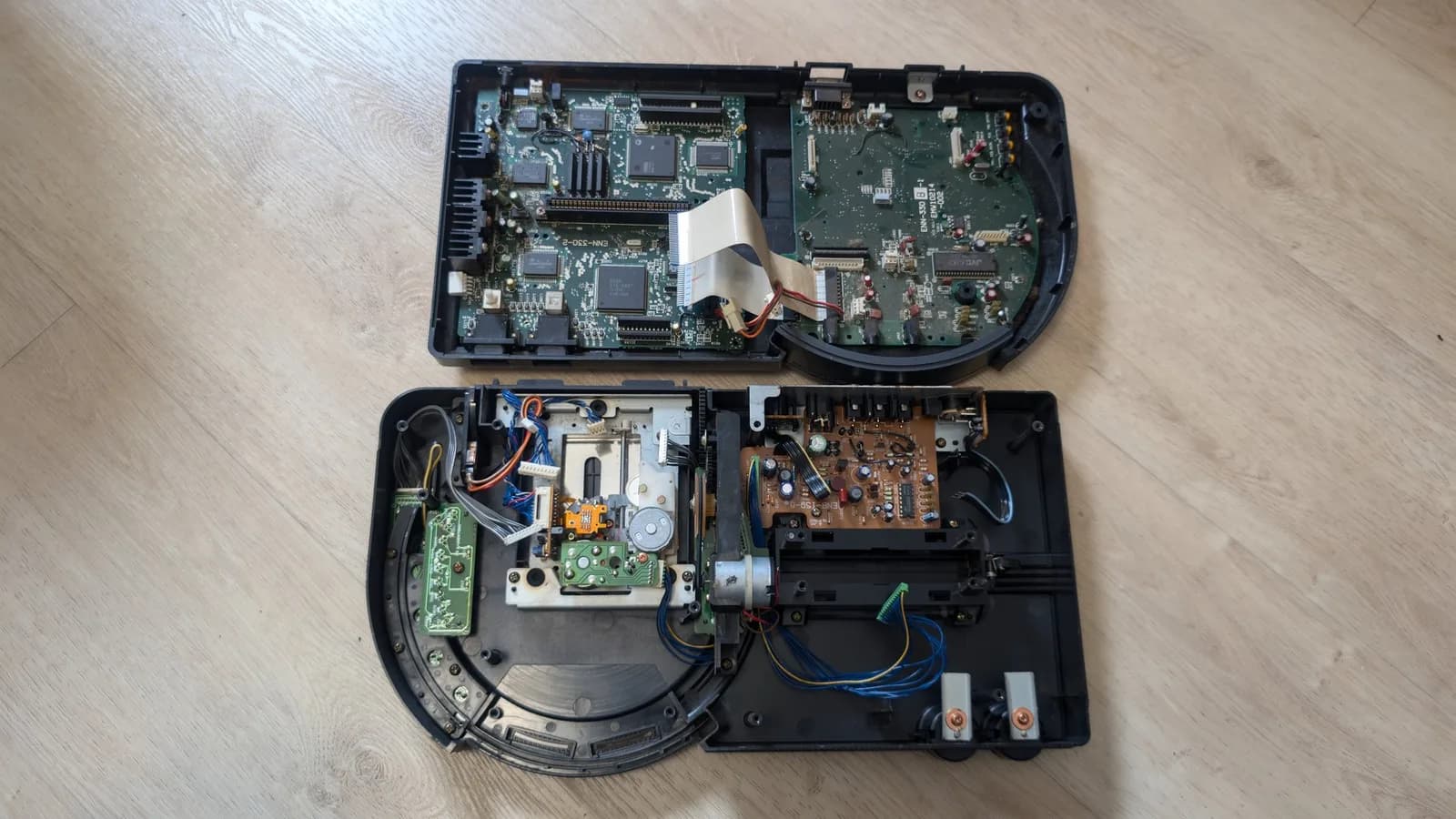 Sega Wondermega HWM-5010 disassembled showing corroded motherboard, CD drive mechanism, and power supply board with visible damage and missing components.