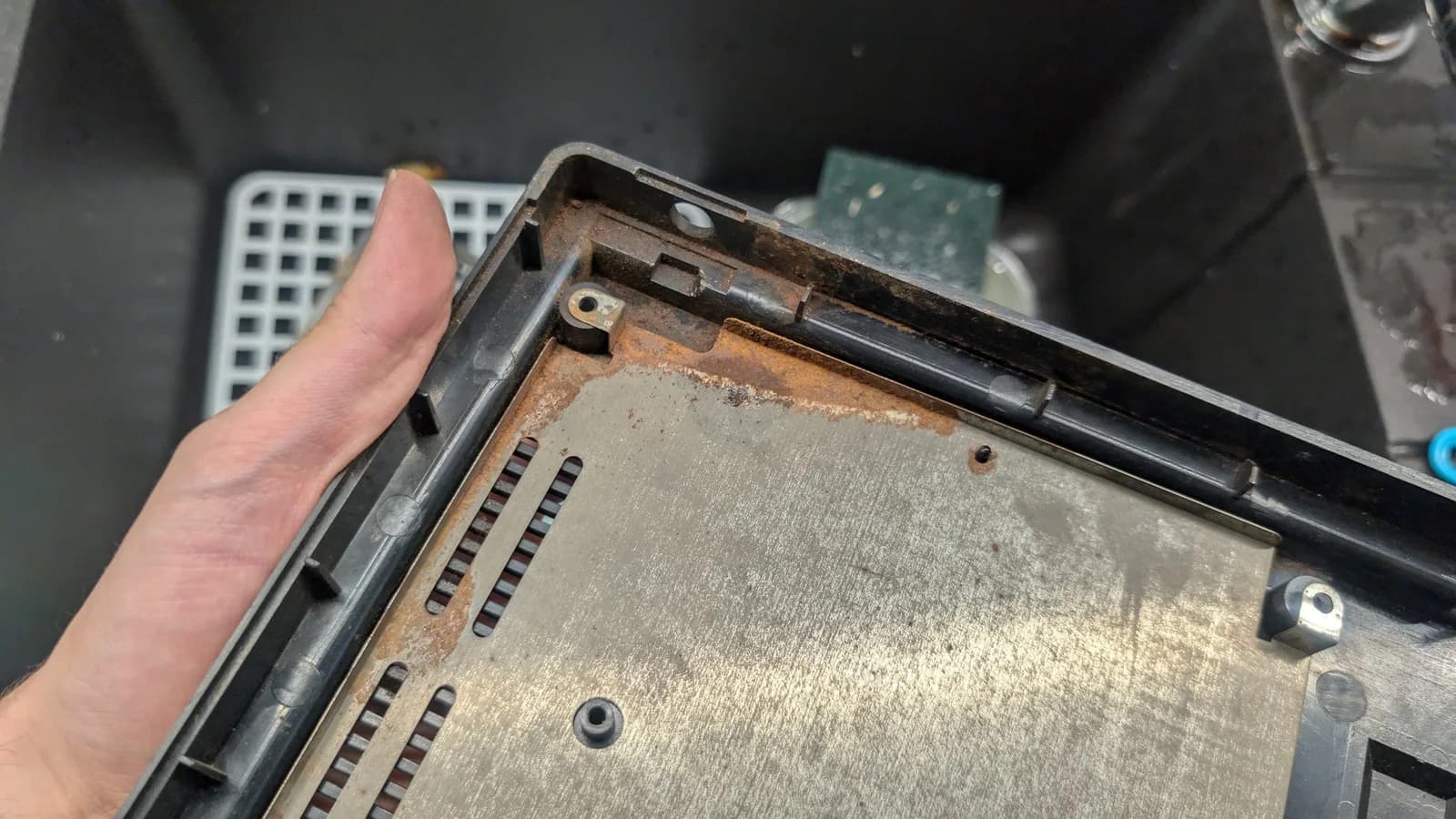 Sega Wondermega HWM-5010 bottom shell interior showing corrosion, missing screws, and damaged board traces during restoration assessment.