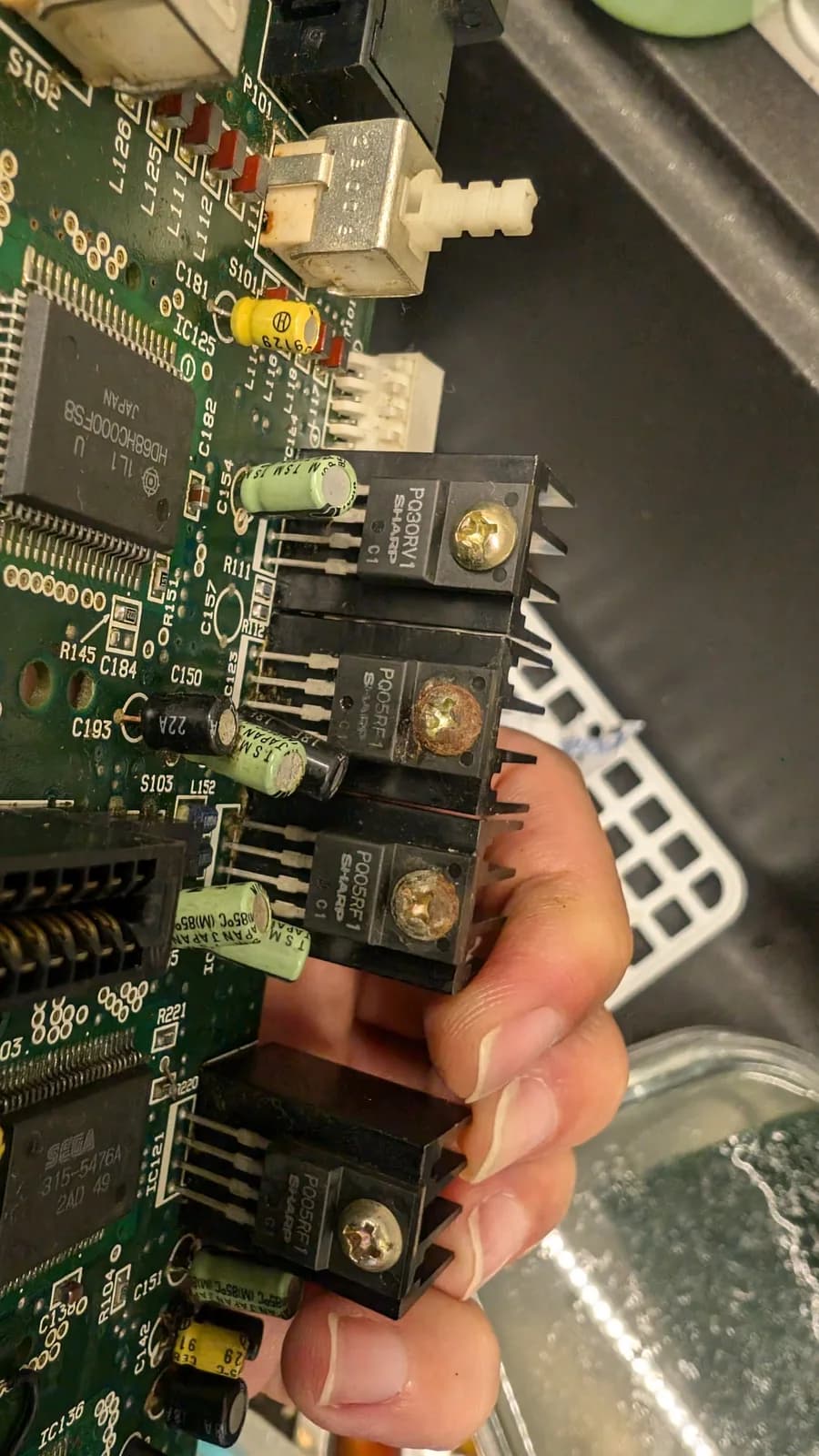 Close-up of Wondermega power supply board showing four black power connector modules with visible corrosion on gold contacts; yellow capacitor visible above.