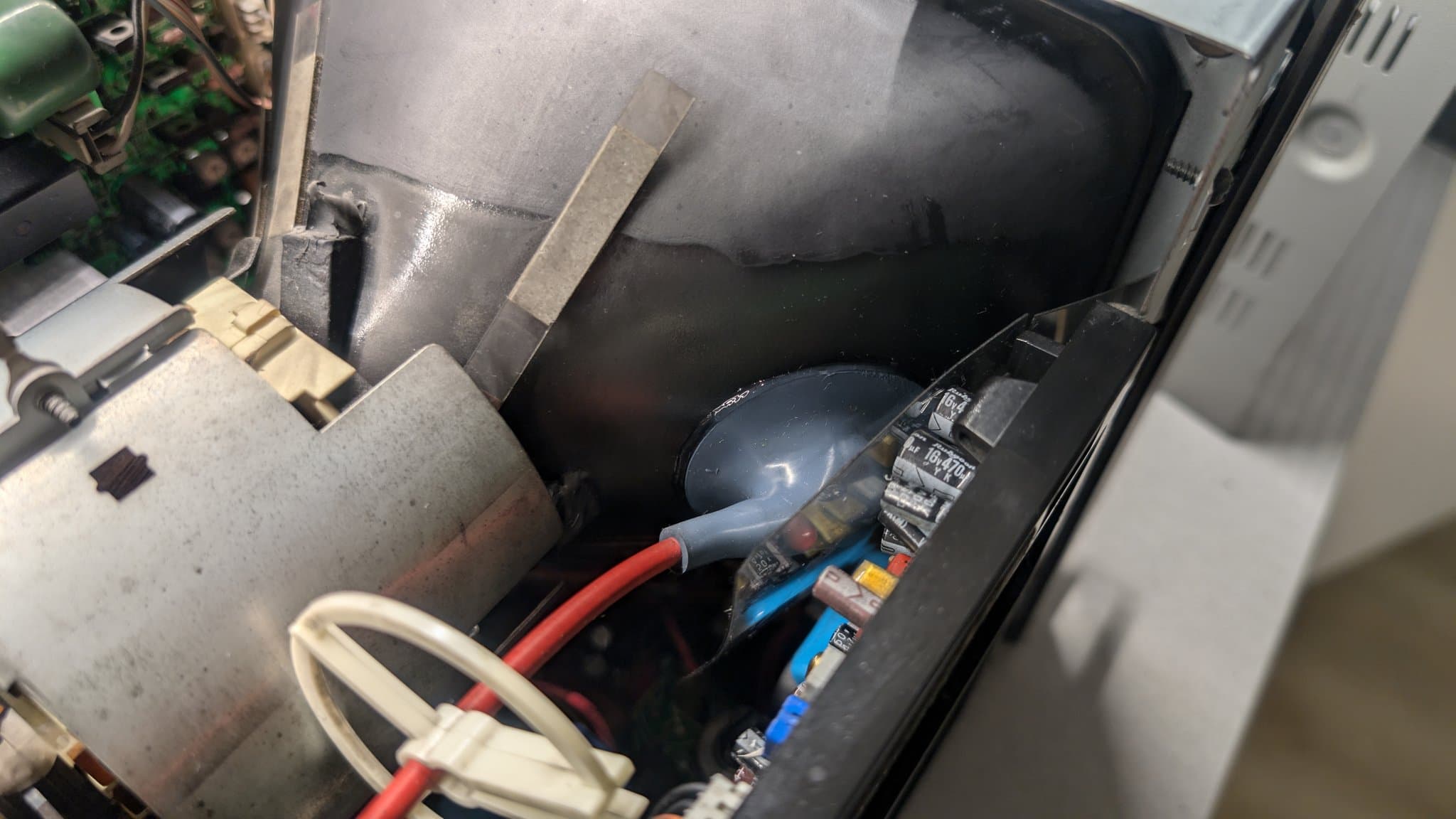 Interior view of PVM-9045QD PSU showing replacement capacitors, dielectric grease application on anode cap, and soldering work on deflection board.