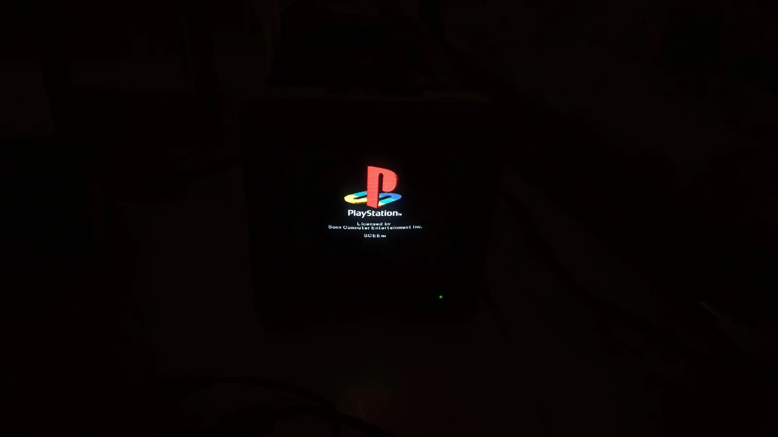 The PlayStation boot logo (SCEE) glowing on the Sony PVM-9045QD in a dark room, used to test the monitor after the PSU recap and neck-board reflow.