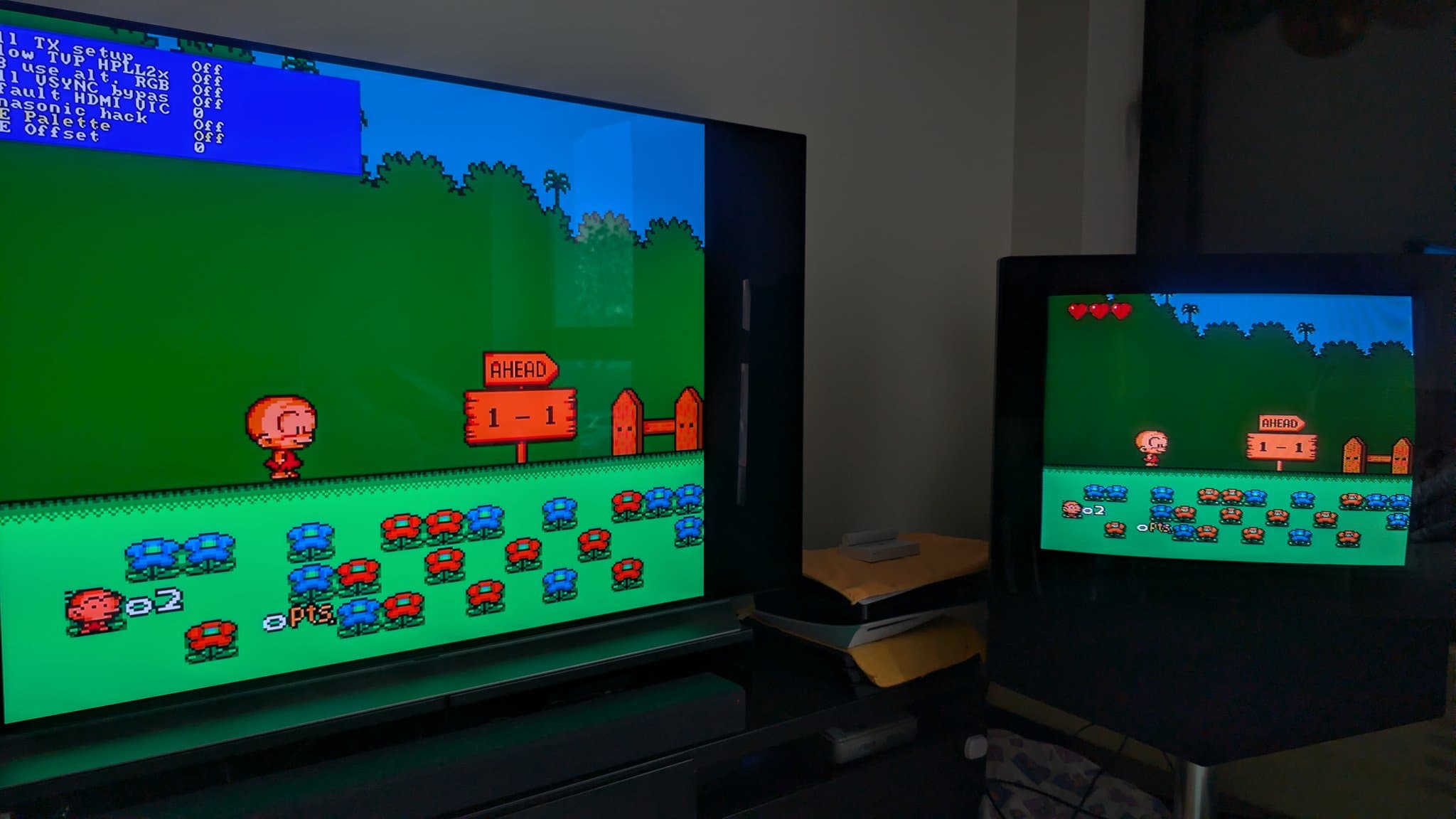Two displays showing PC Engine game with experimental composite palette emulation on modded OSSC; left monitor larger, right smaller, both displaying identical green landscape scene.