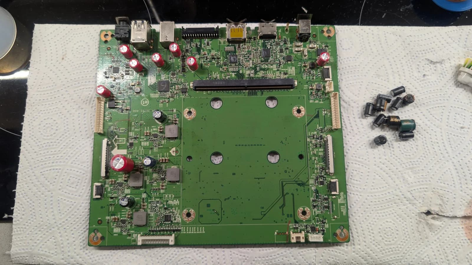 Asus PG27UQ mainboard with replaced capacitors; removed CapXon units beside board on white mat.