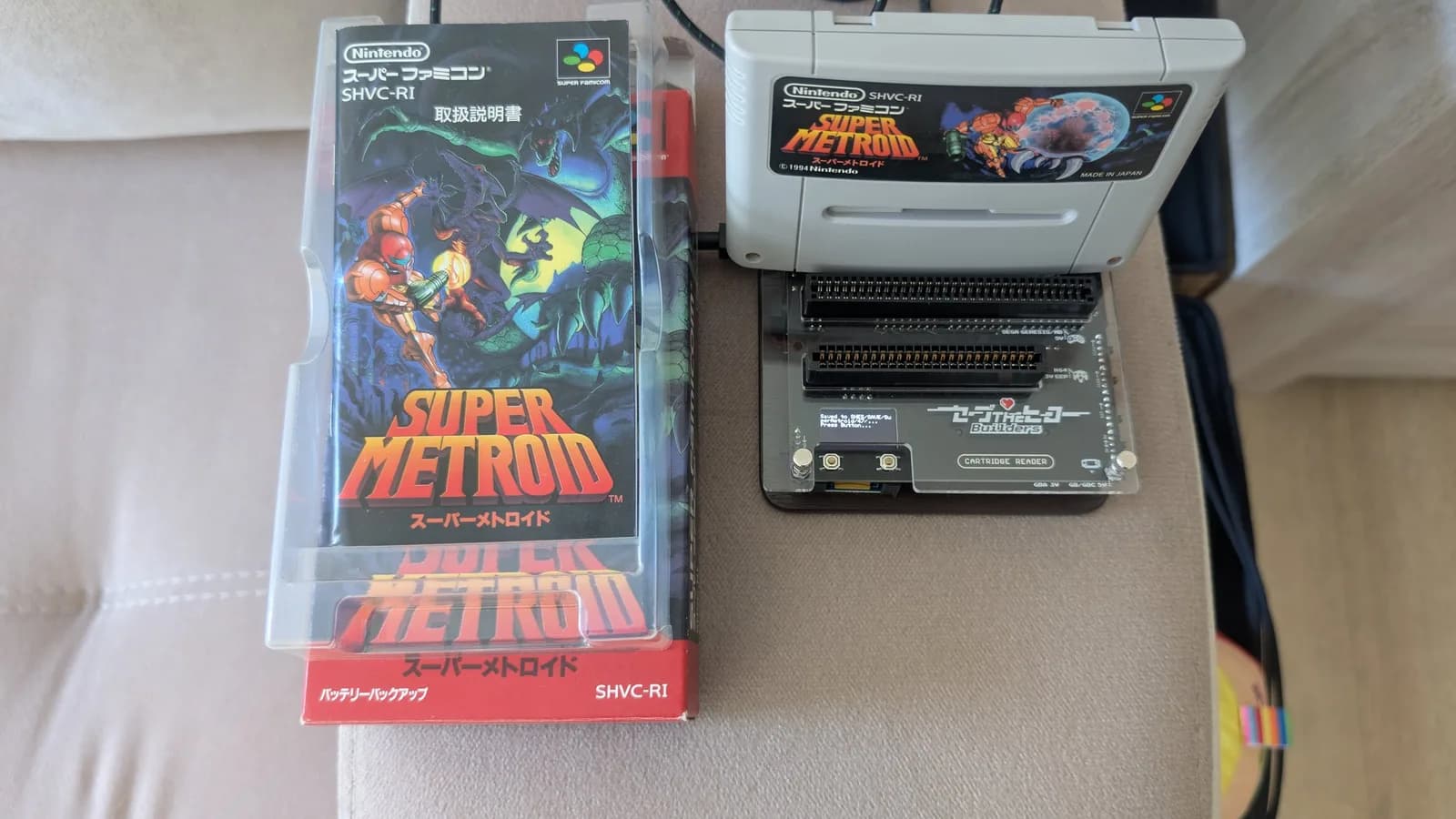 Boxed Super Metroid with its manual, the cartridge itself inserted into the Save The Hero Builders OSCR V3 cartridge reader to back up the save.